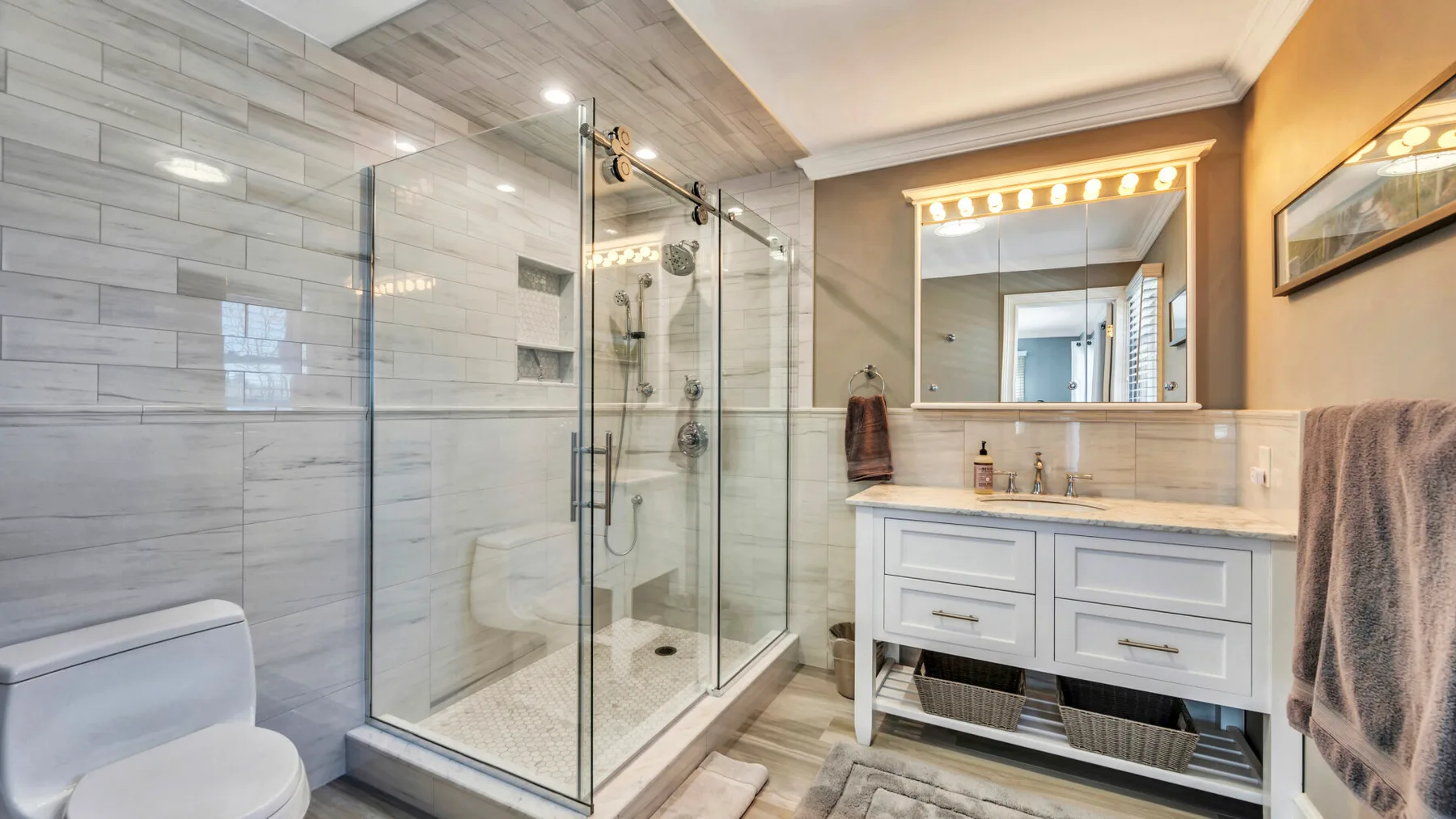 A bathroom with a glass shower, toilet, and vanity.
