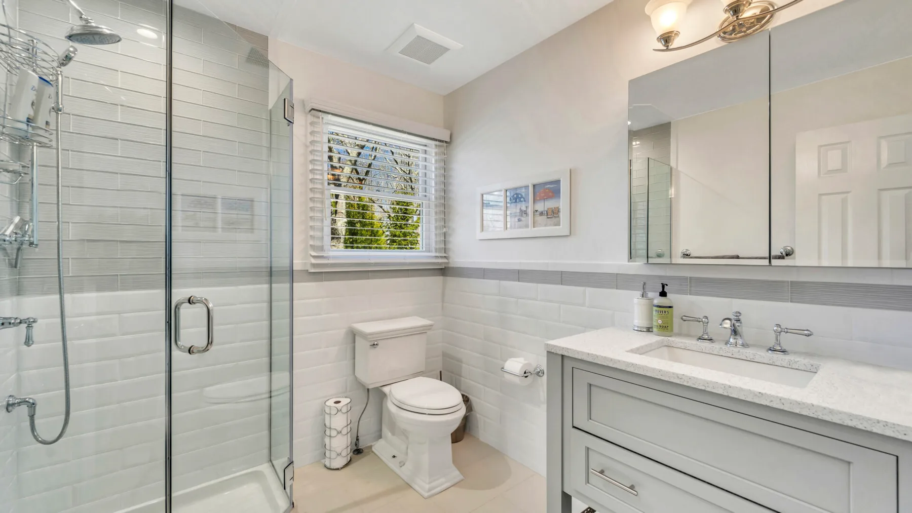 A bright bathroom with a glass shower, toilet, and wide vanity.