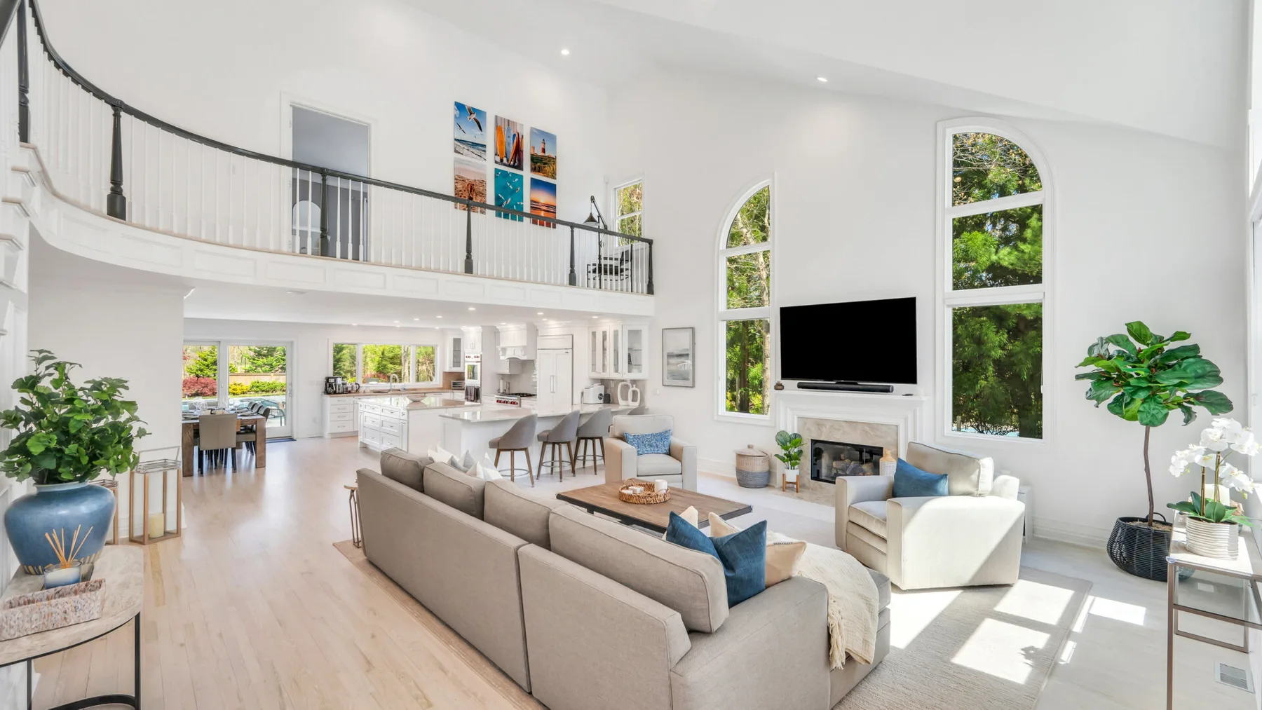 A bright living room with seating, a television, and tall arched windows.