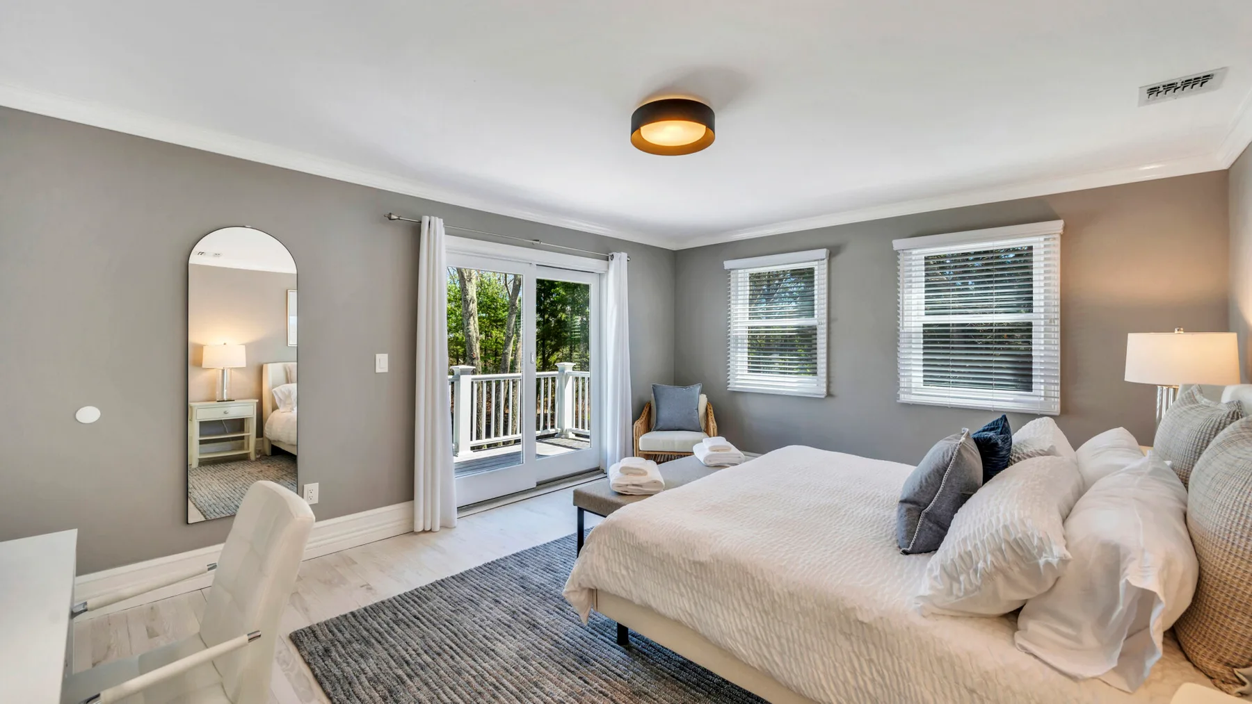 A bedroom with a bed, a glass door, and windows overlooking greenery.