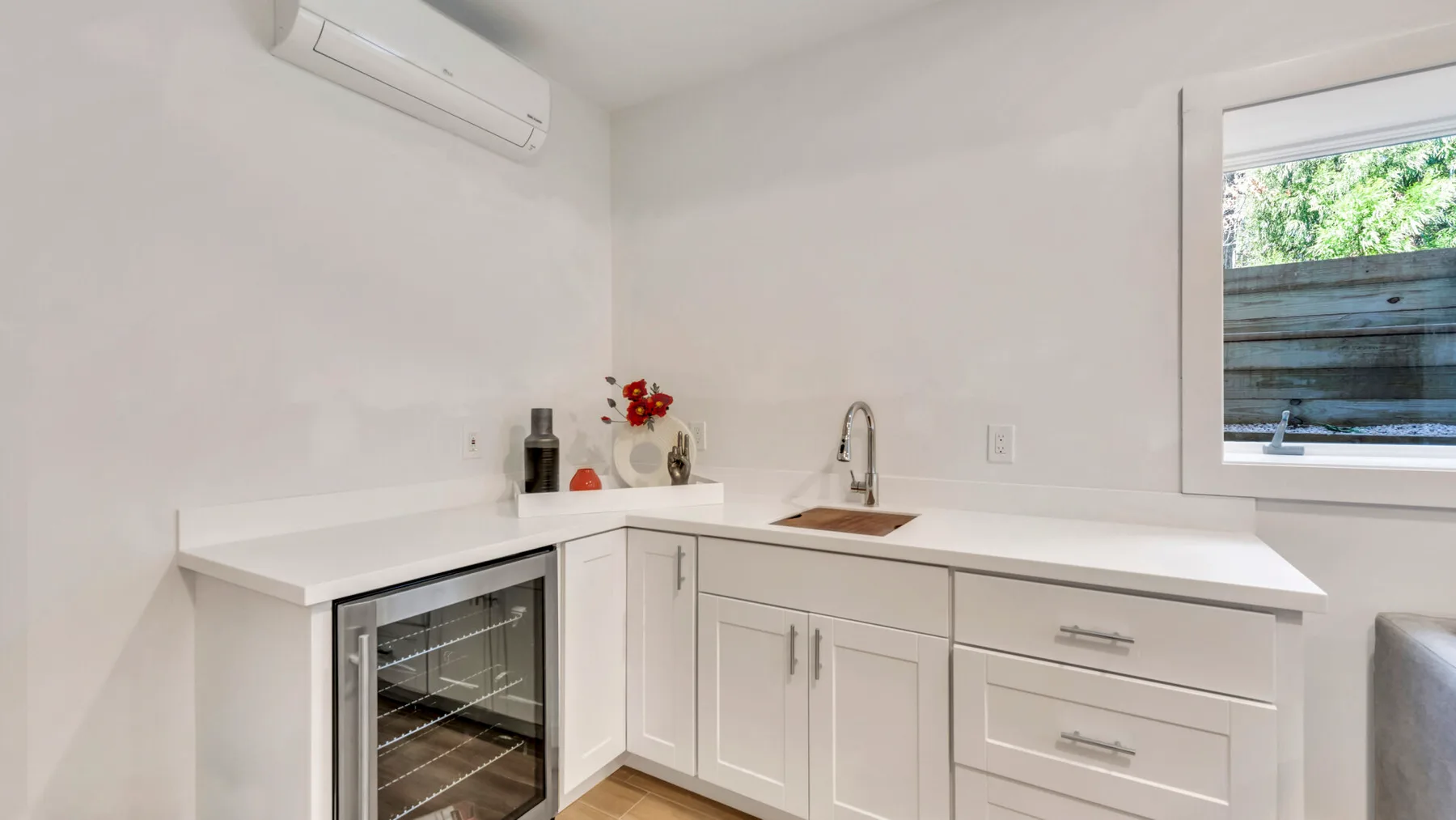 A bright kitchenette with white cabinets, a countertop, and a small sink.