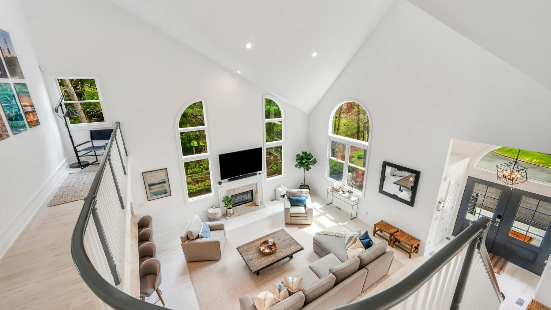 A bright living room with vaulted ceilings, arched windows, and seating around a coffee table.