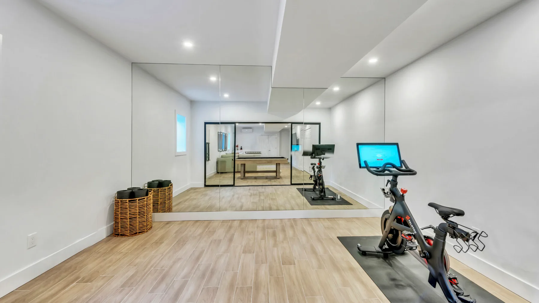 A bright home gym with exercise bikes and a mirrored wall.