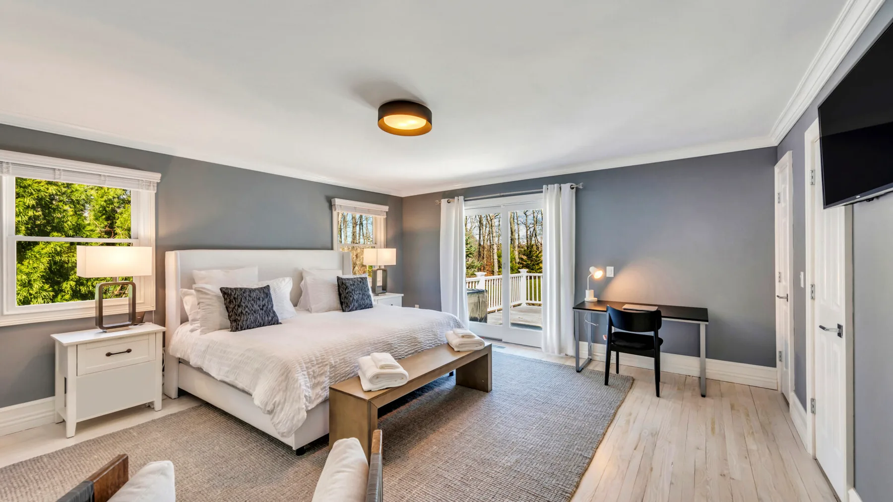 A bedroom with a large bed, bedside tables, and doors opening onto a balcony.