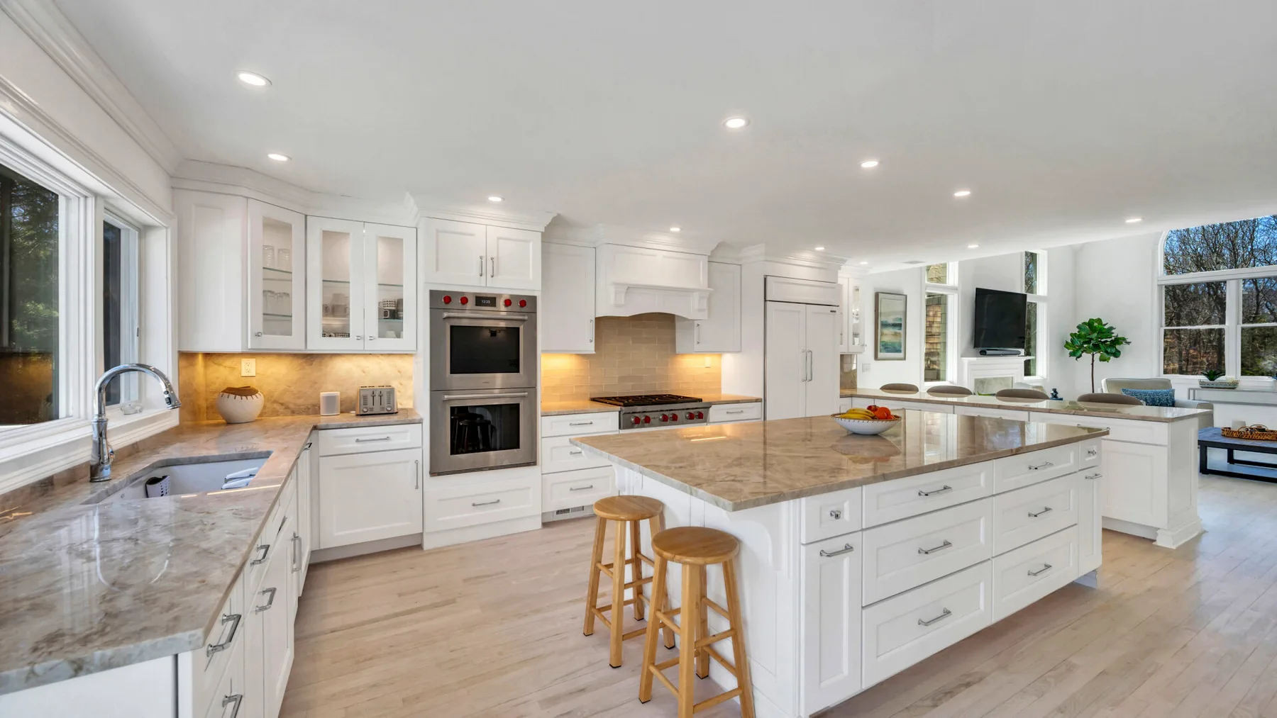 A bright kitchen with white cabinetry, stone countertops, and a central island.