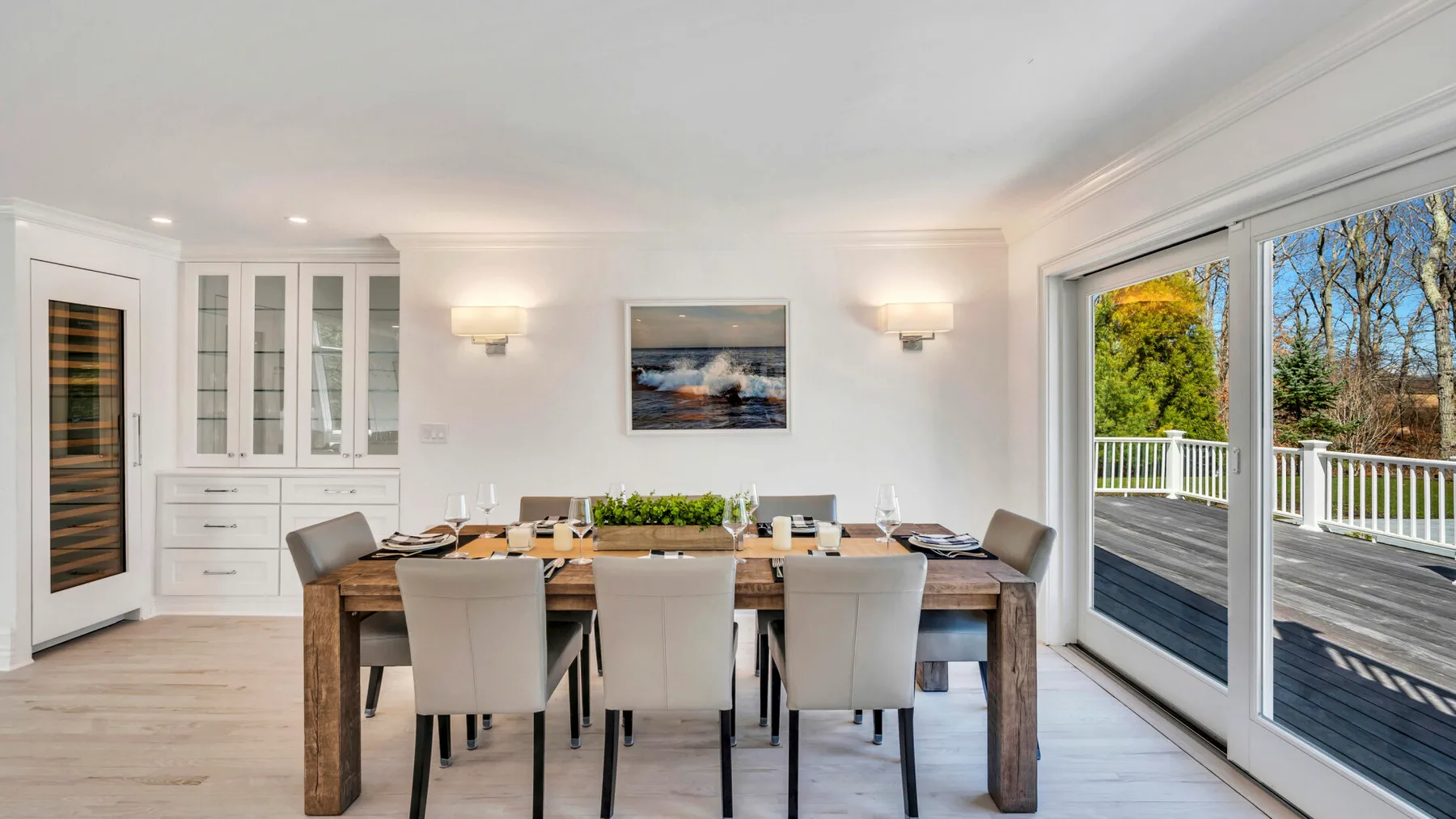 A dining room with a long table set beside large sliding glass doors.