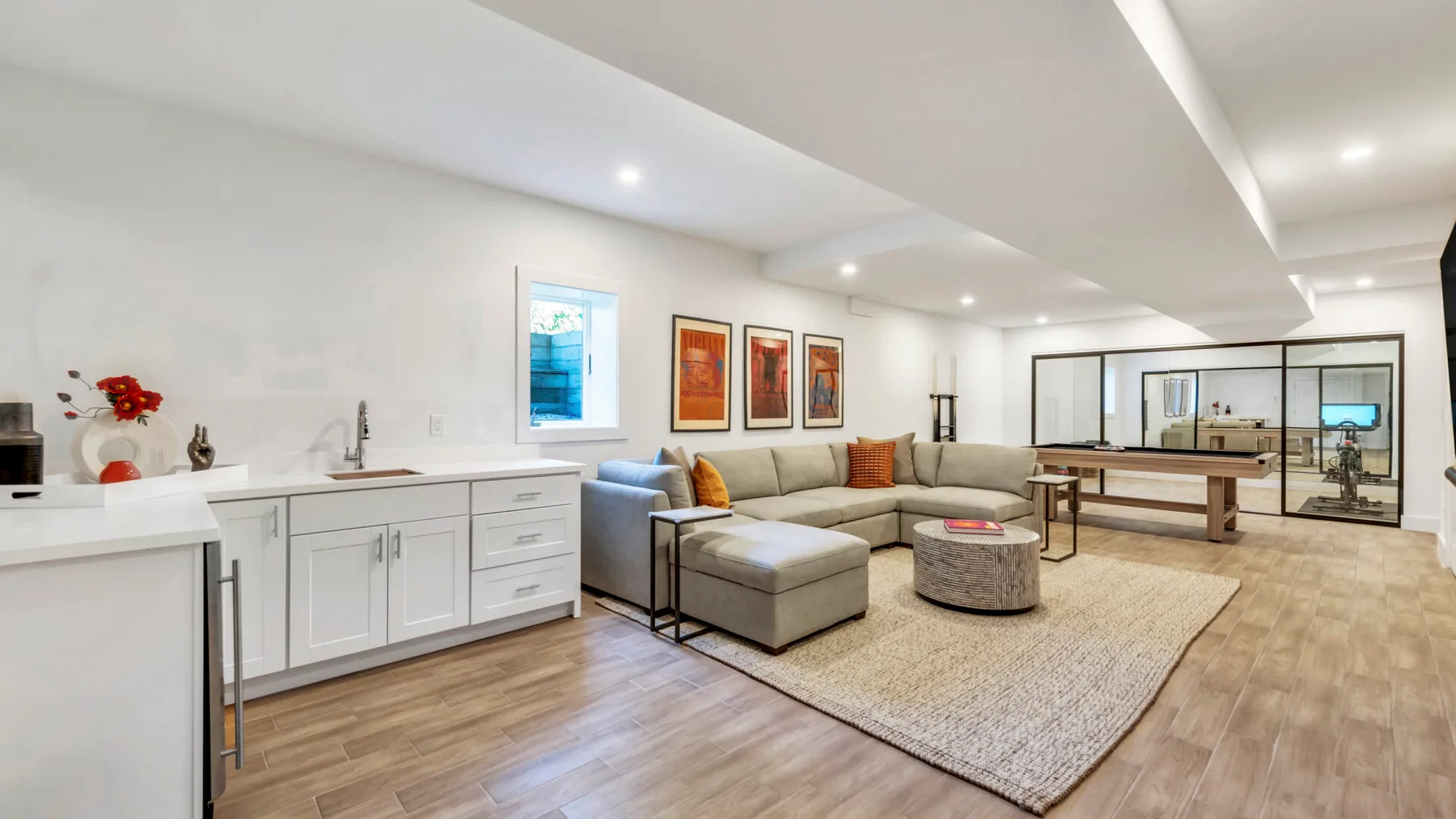 An open-plan living area with a sectional seating arrangement, coffee table, and kitchen counter.