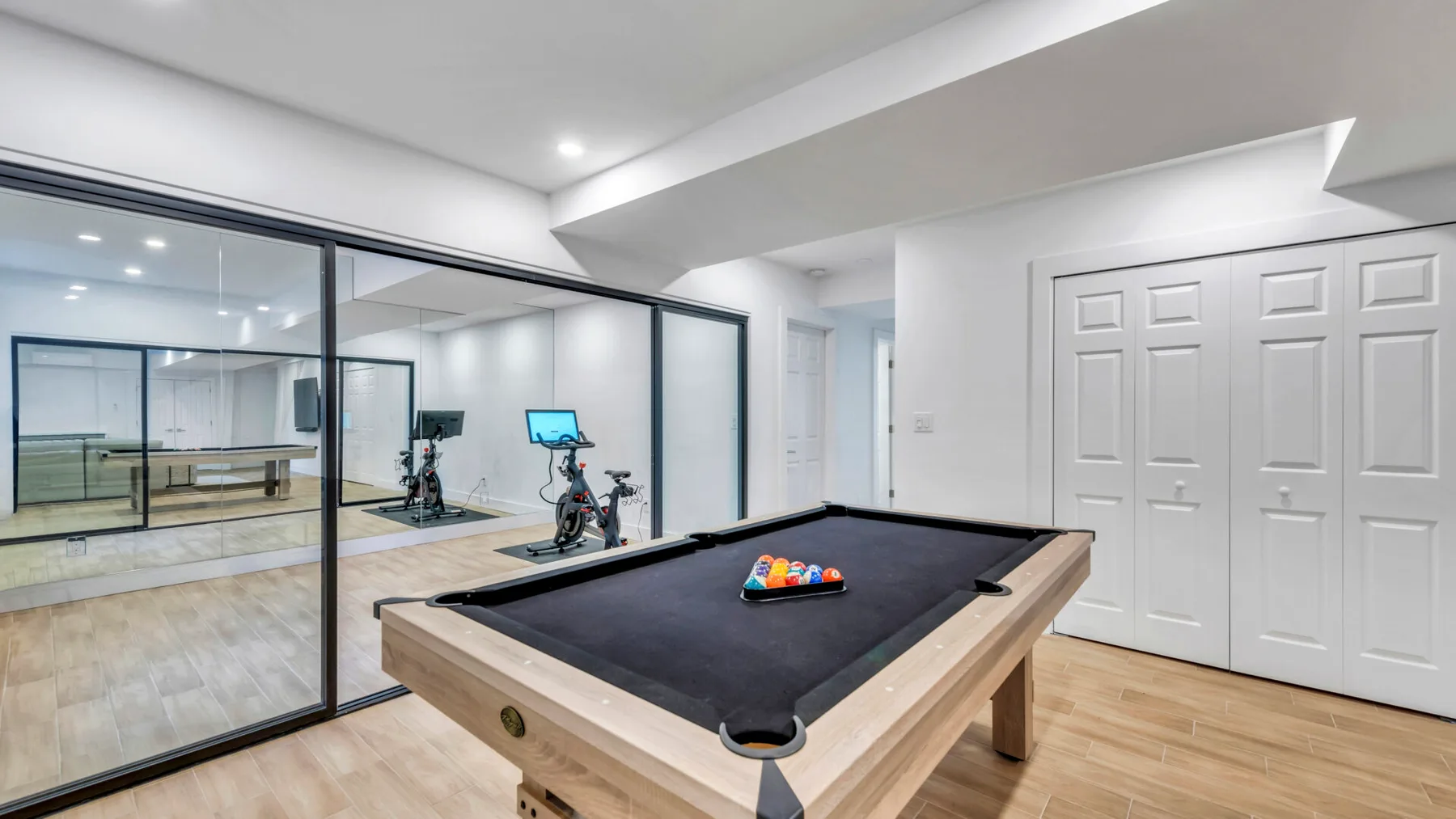 A billiards table sits in a bright recreation room with mirrored walls.