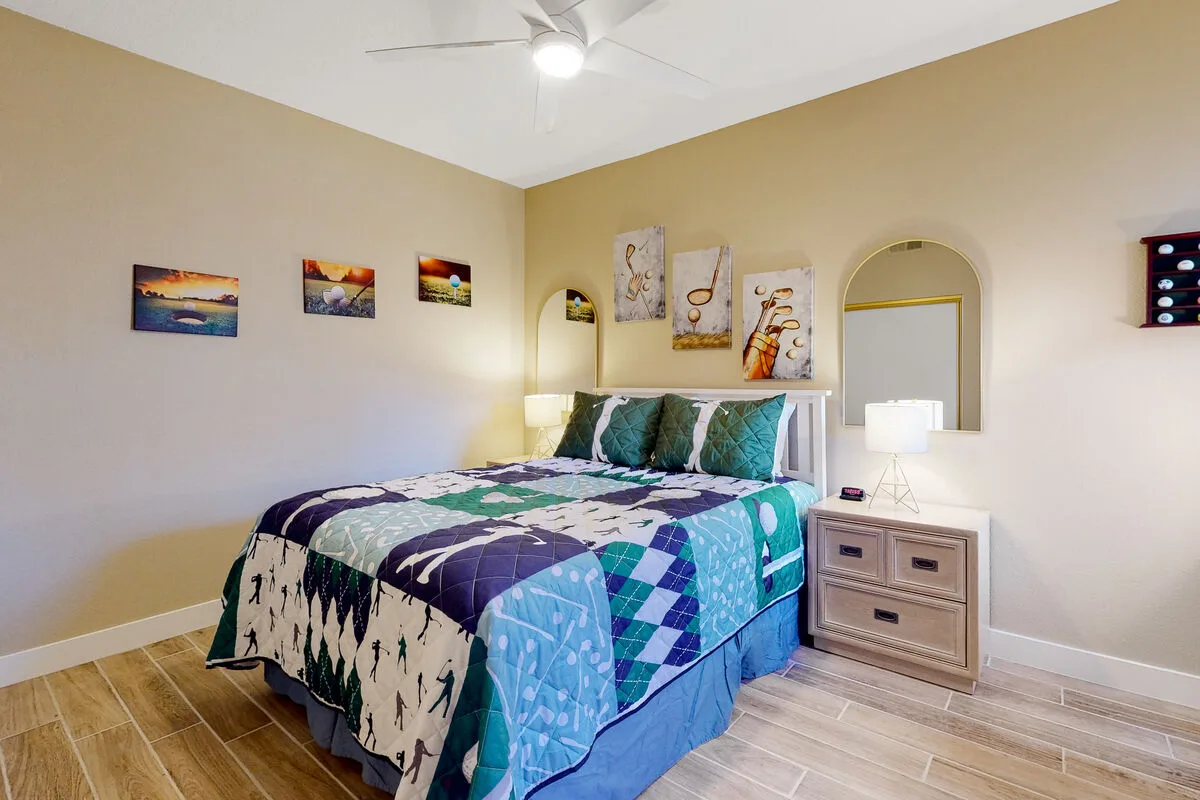 Un dormitorio con una cama vestida con ropa de cama azul y verde azulado y una mesita de noche.