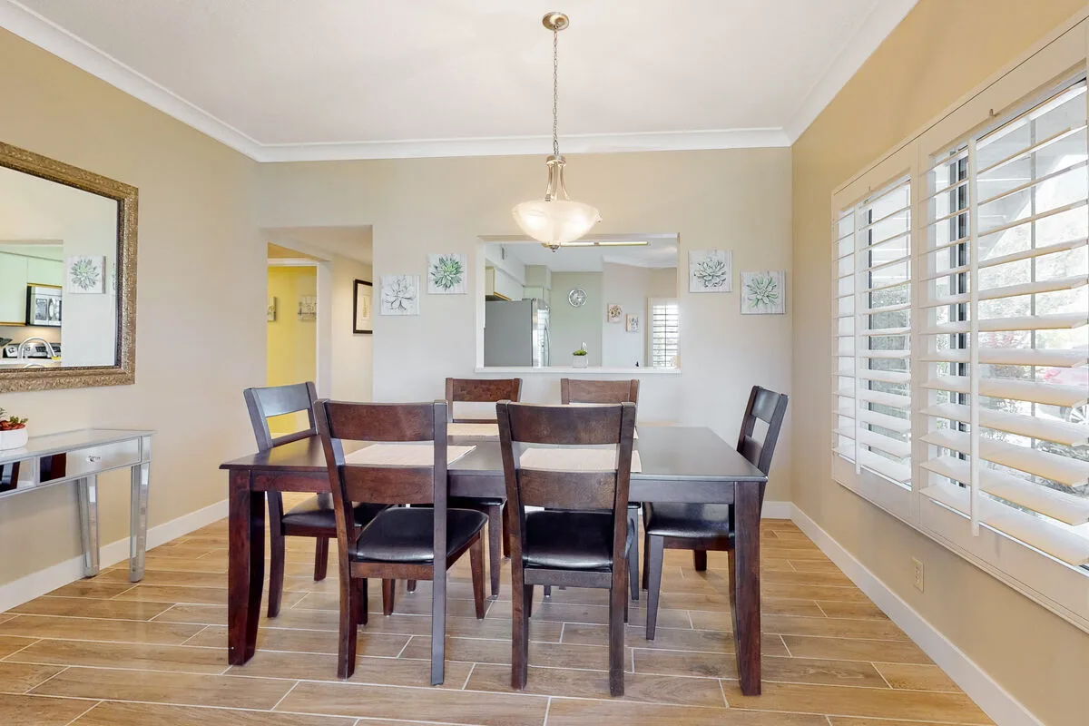 Comedor con una mesa de madera y sillas junto a grandes ventanas.