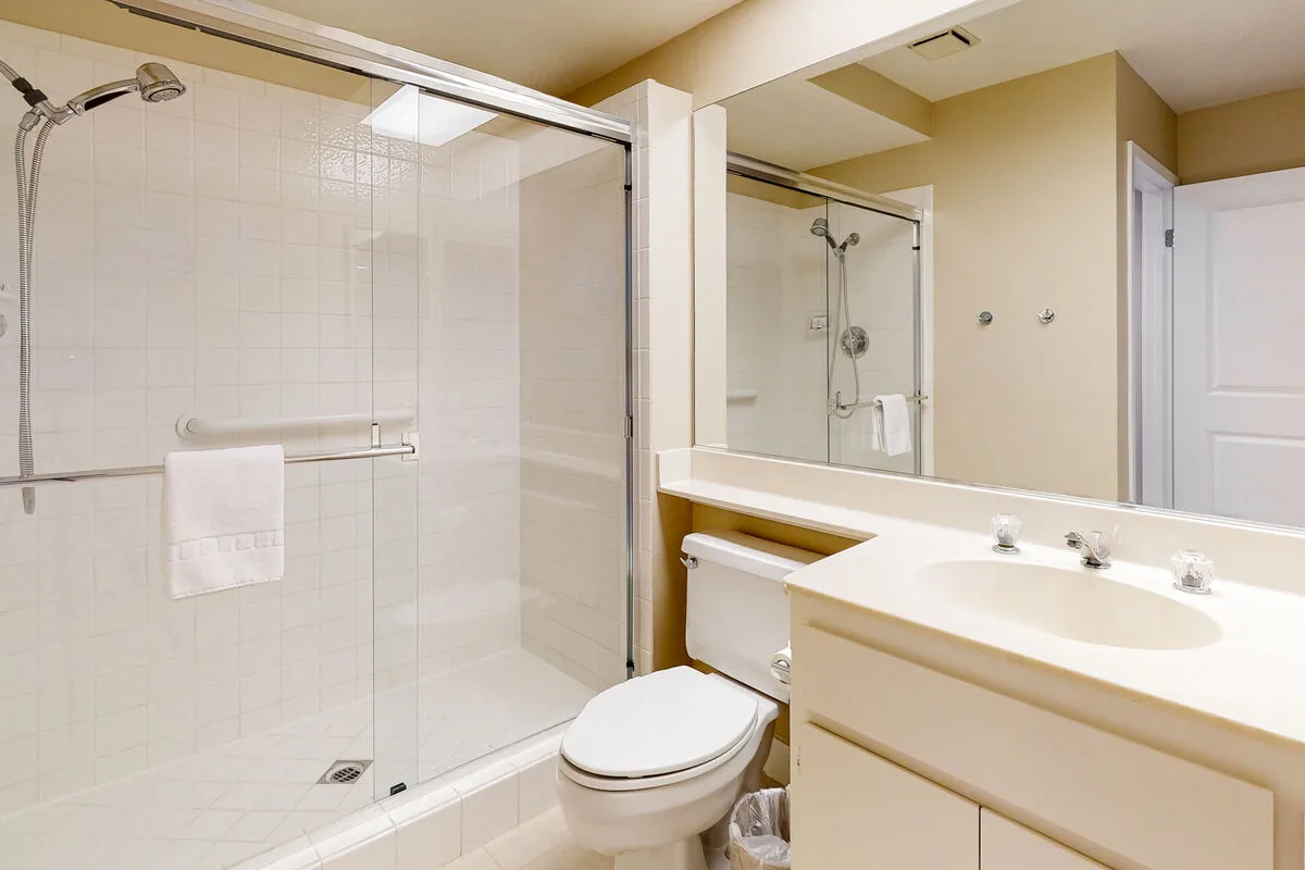 Un baño luminoso con ducha de vidrio y lavabo.