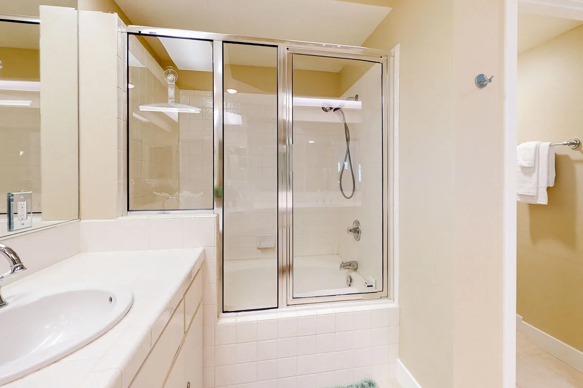 Un baño con un lavabo y una ducha con mampara de vidrio.