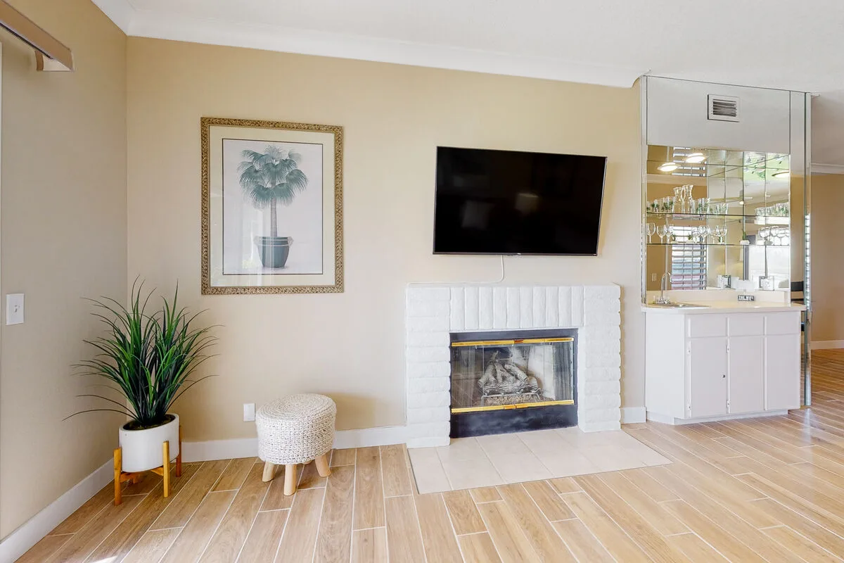 Sala de estar con chimenea, televisor montado en la pared y planta en maceta.