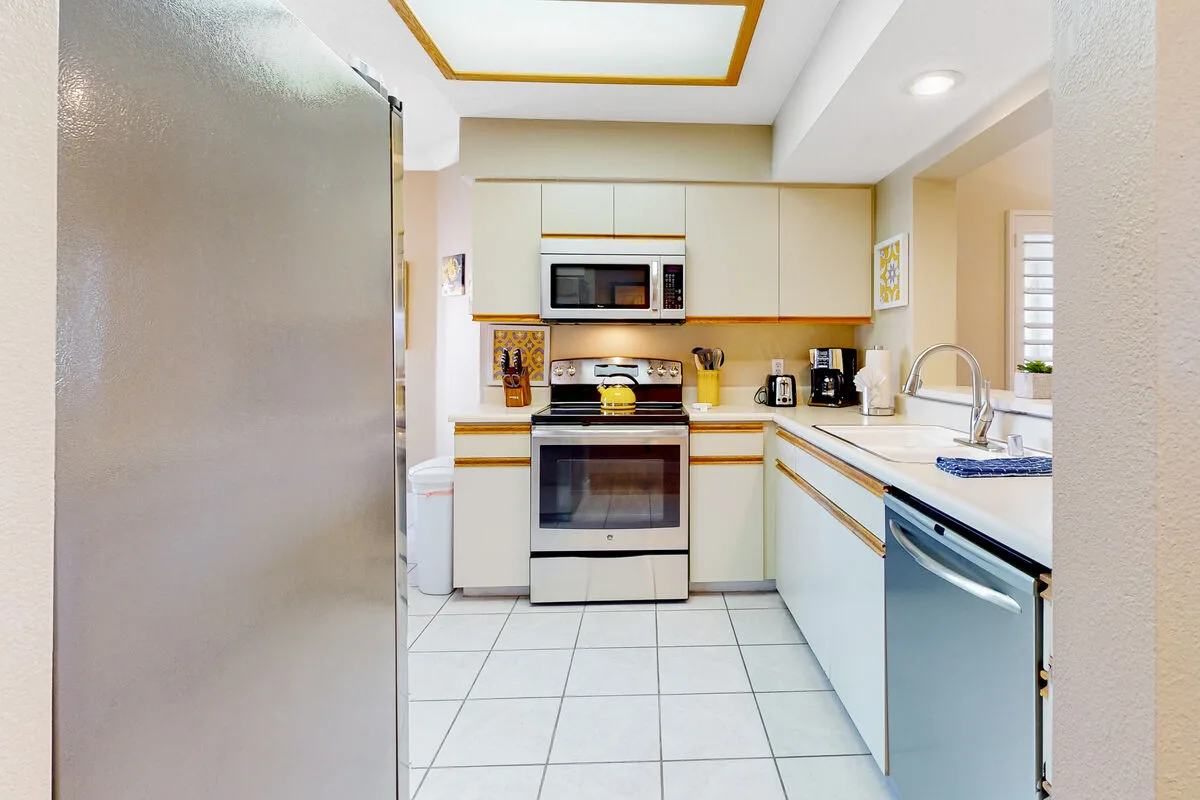 Una cocina luminosa con gabinetes blancos, horno y piso de baldosas.