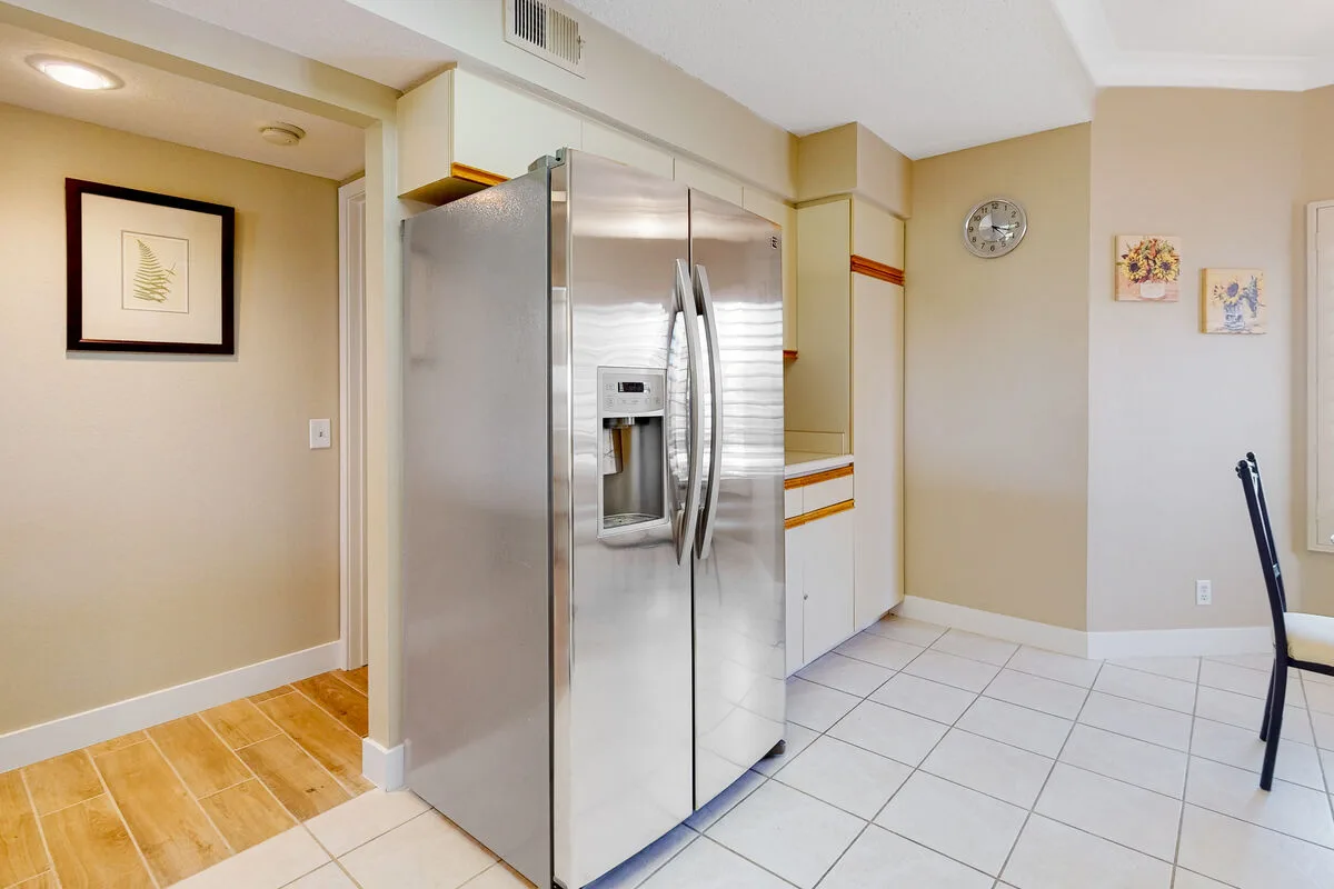 Una cocina con un refrigerador de acero inoxidable y piso de baldosas.