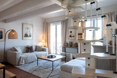 A bright living room with seating, a coffee table, and large windows.