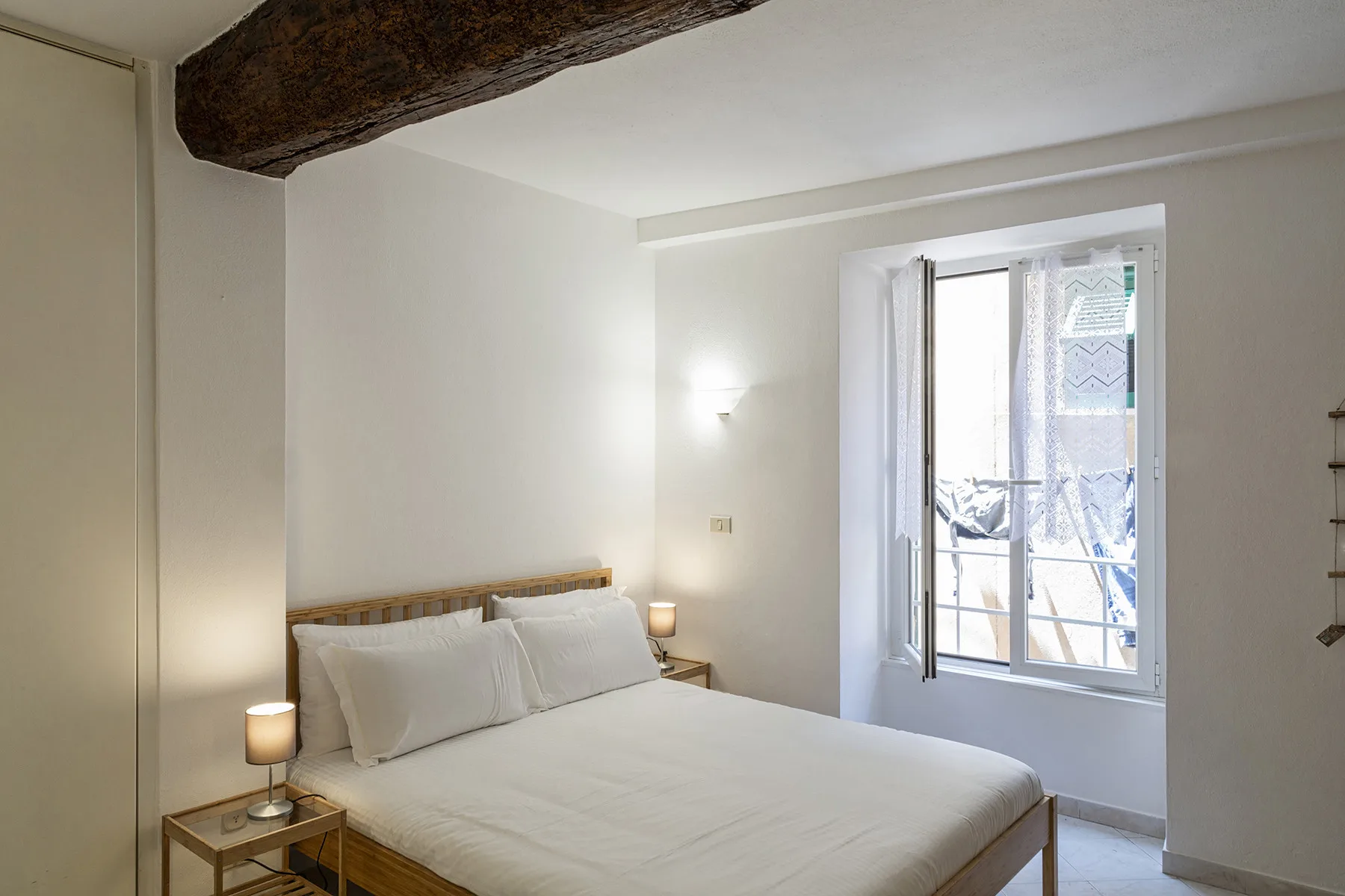 A bedroom with a double bed and a bright window.
