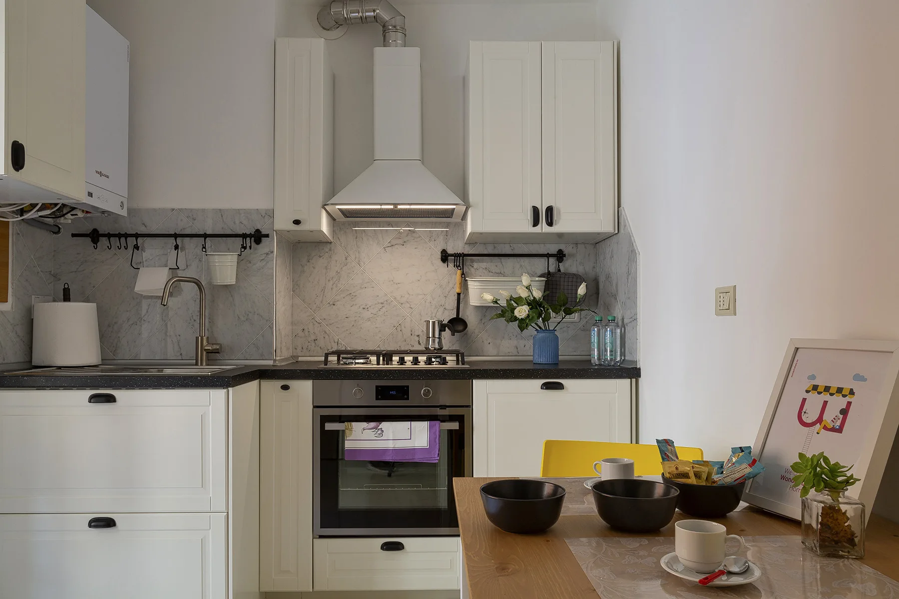 Una cocina luminosa con armarios blancos, estufa y mesa de comedor.
