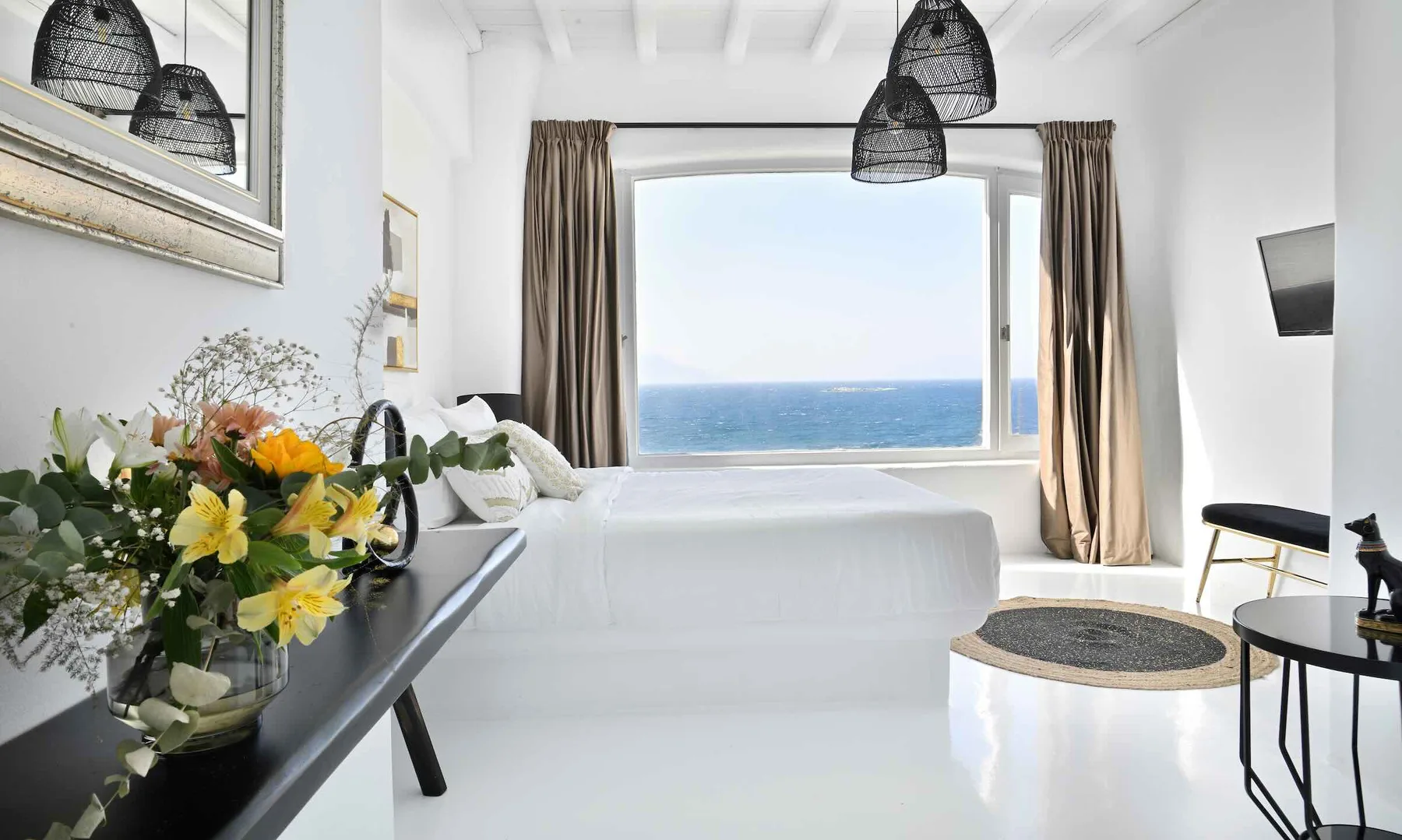 A bright bedroom with a large window overlooking the sea.