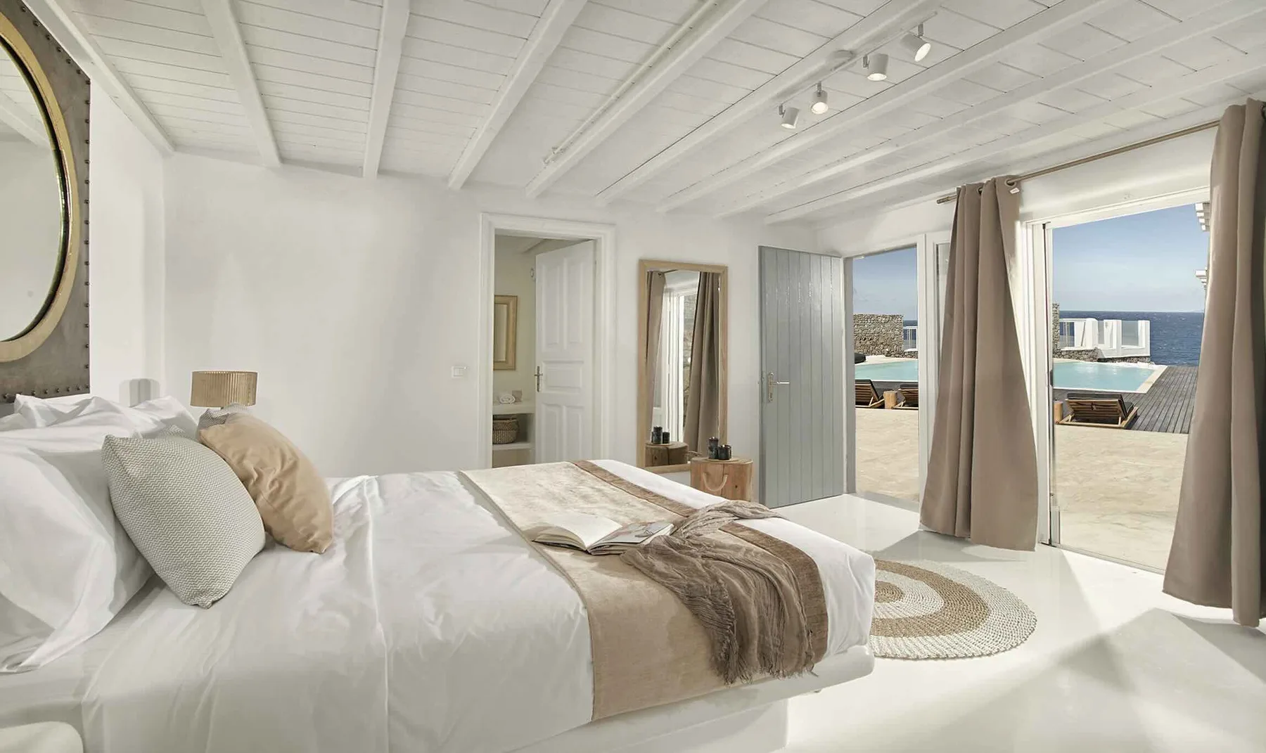 A bright bedroom opens onto a terrace overlooking the sea.