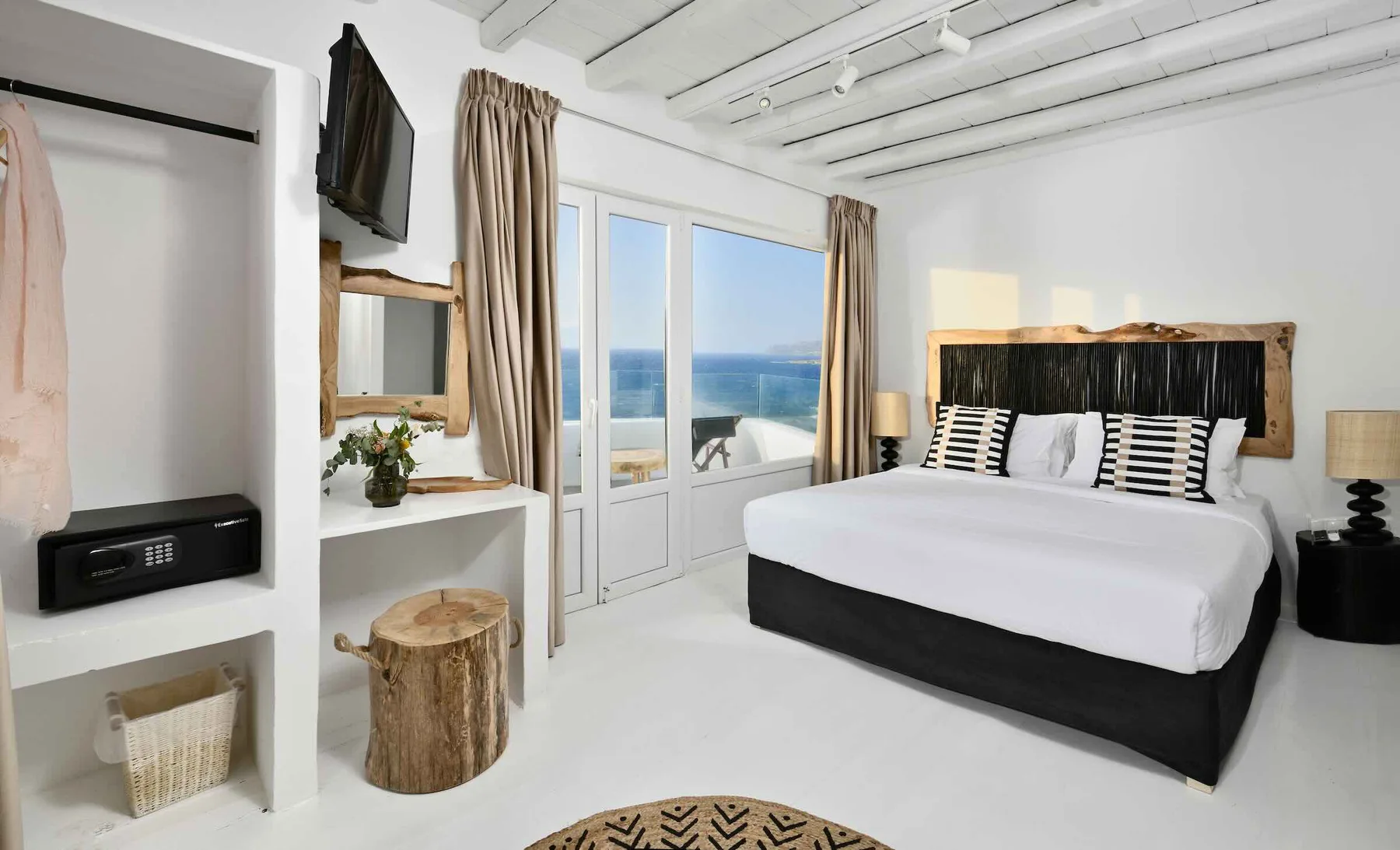 Un dormitorio con una cama grande frente a puertas de vidrio con vista al océano.