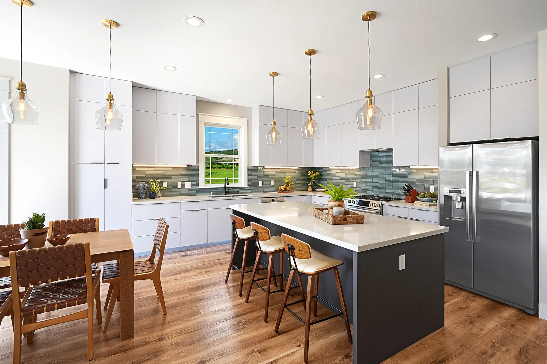 Una cocina luminosa con una isla grande, una mesa de comedor y lámparas colgantes.