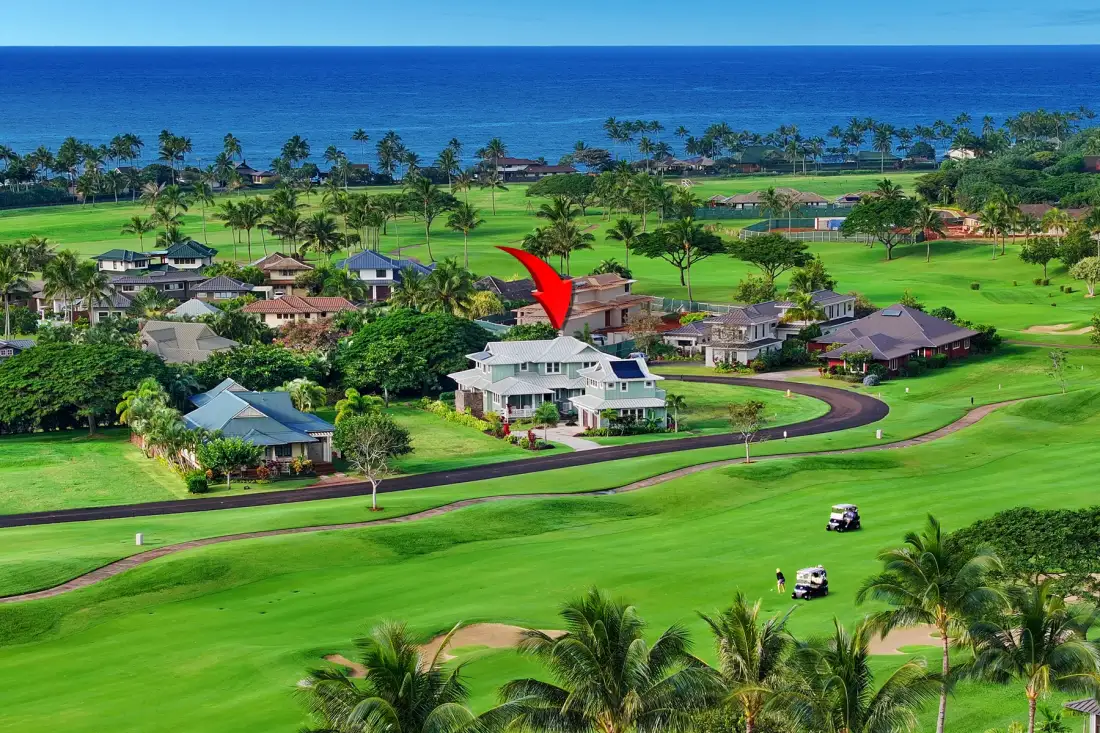 Un campo de golf costero con calles verdes, palmeras y casas cercanas.