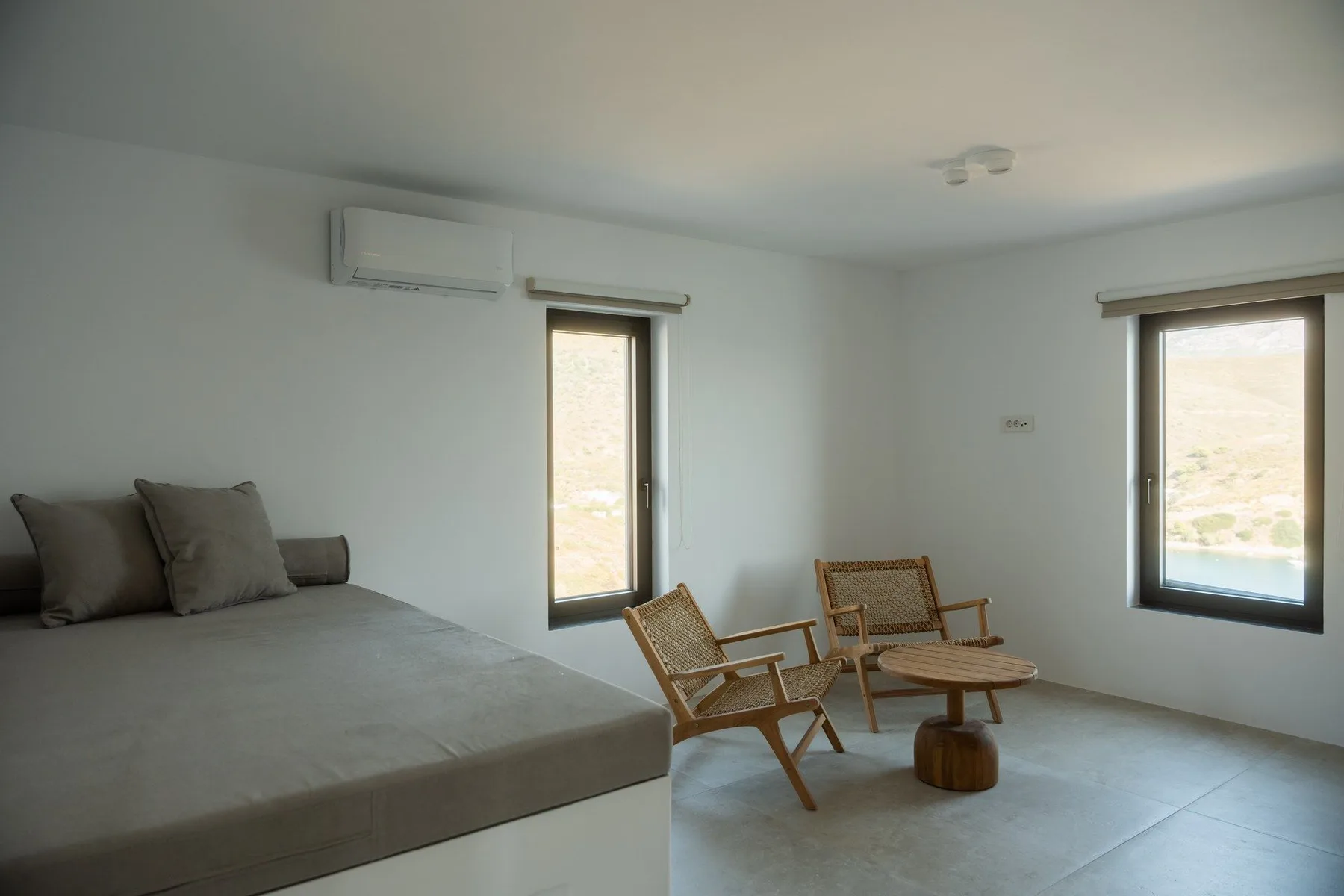 A bedroom with a bed and seating beside two windows.