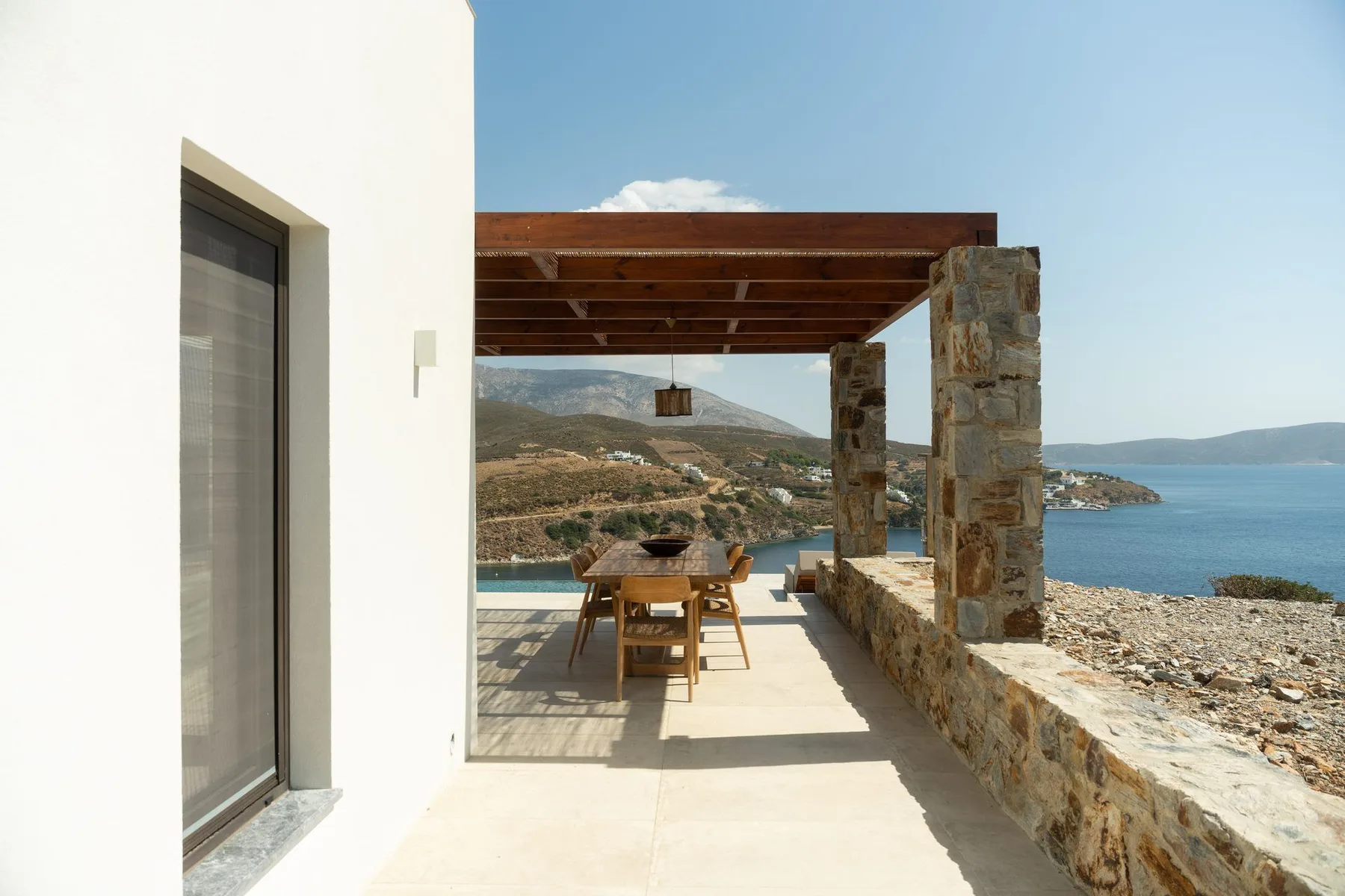 A shaded outdoor dining area overlooks the sea.