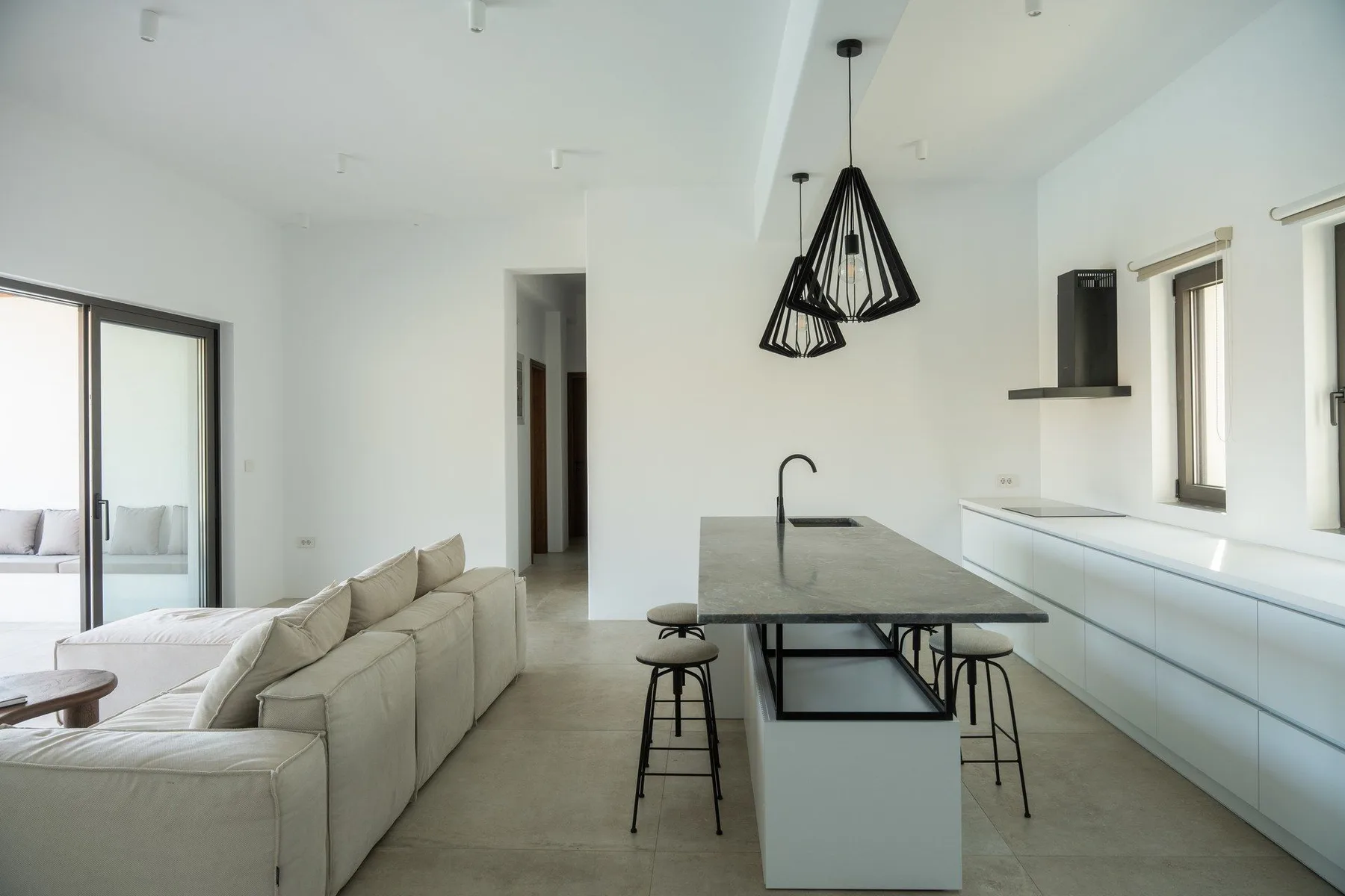 A bright kitchen and living area with an island and pale seating.