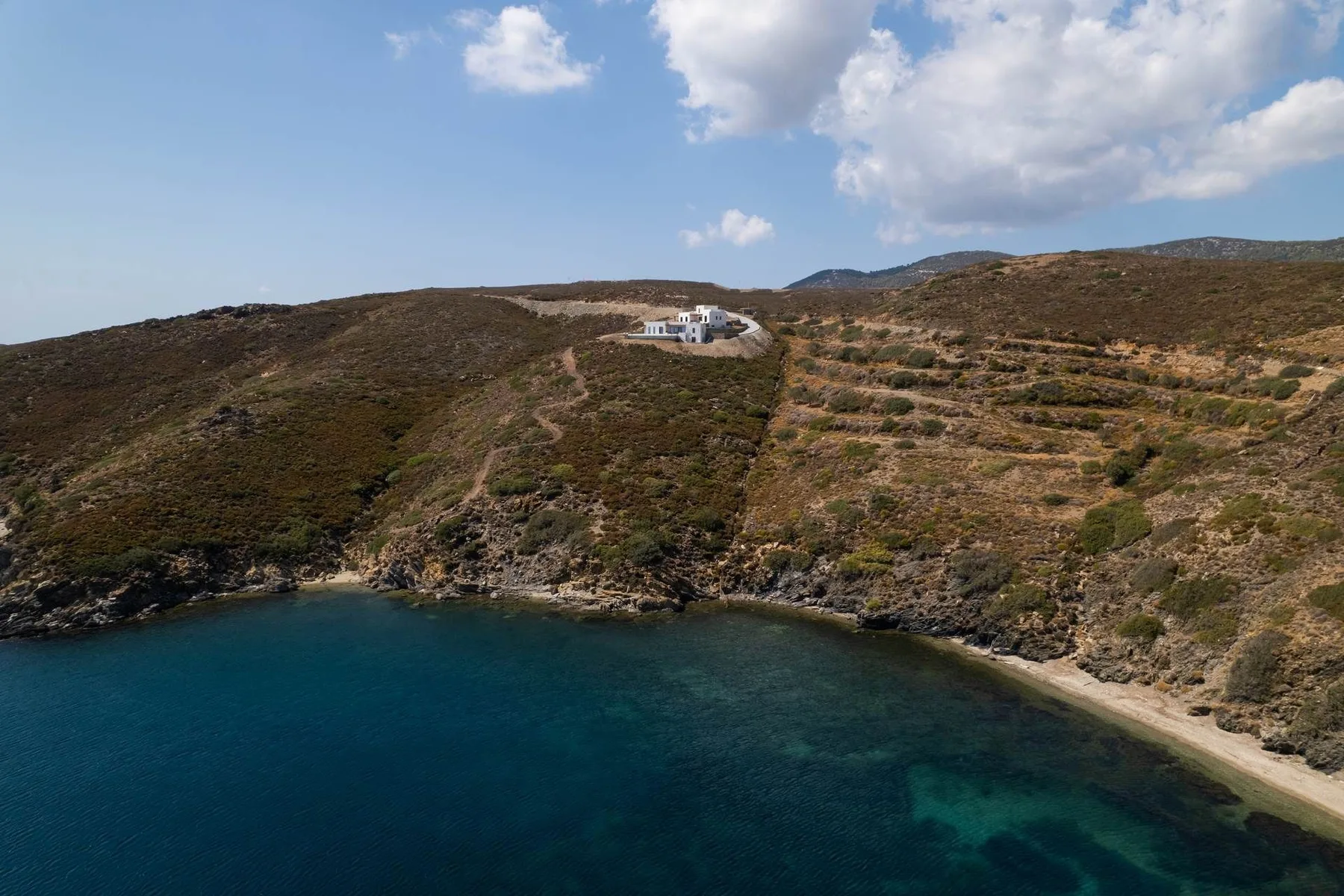 Aerial view of a secluded-looking cove beneath a rugged hillside.