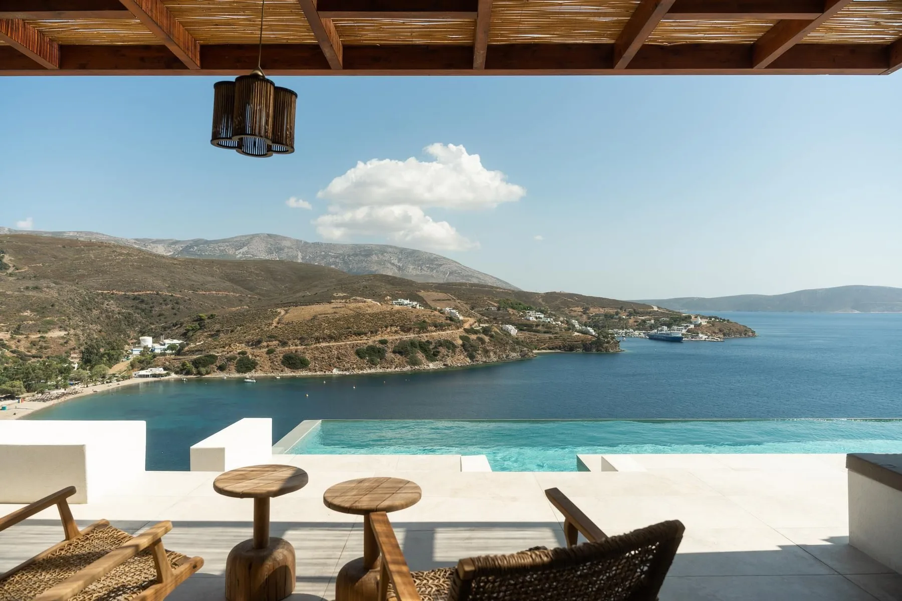 A seaside terrace overlooks a bay, with a swimming pool along the edge.