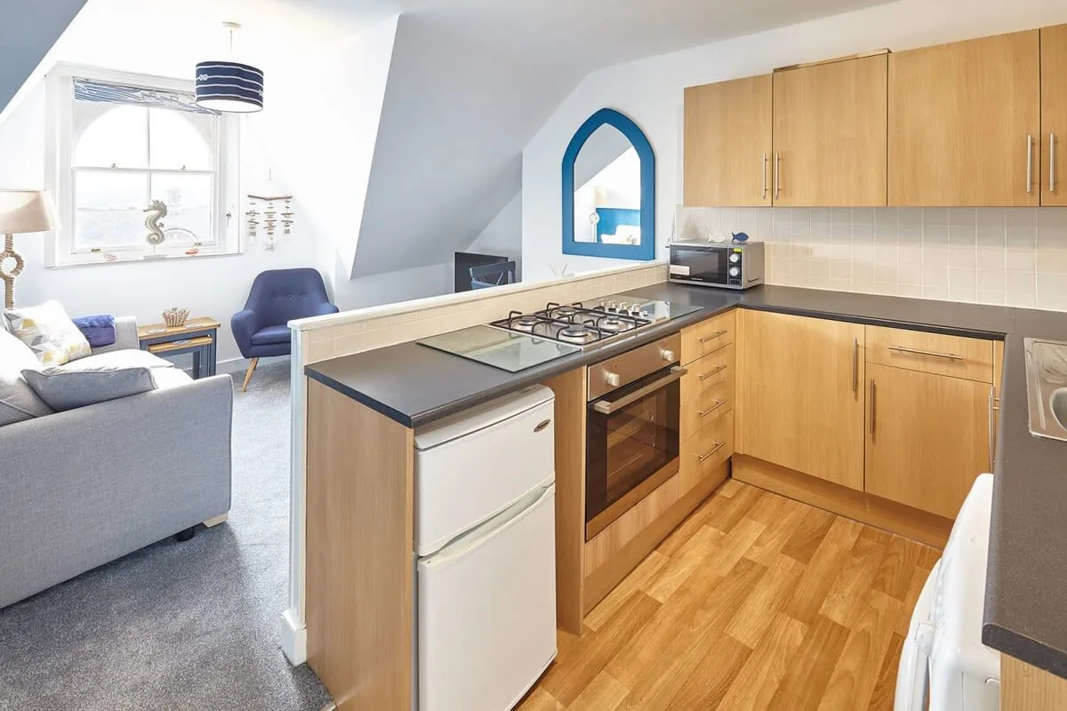 A compact kitchen with a breakfast counter opens onto a small sitting area.