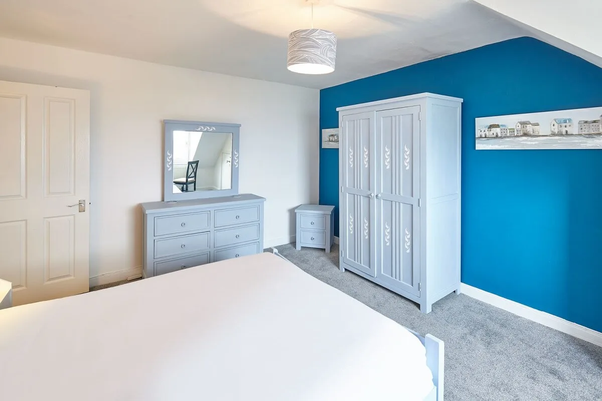 Bedroom with a bed, wardrobes, and a blue accent wall.