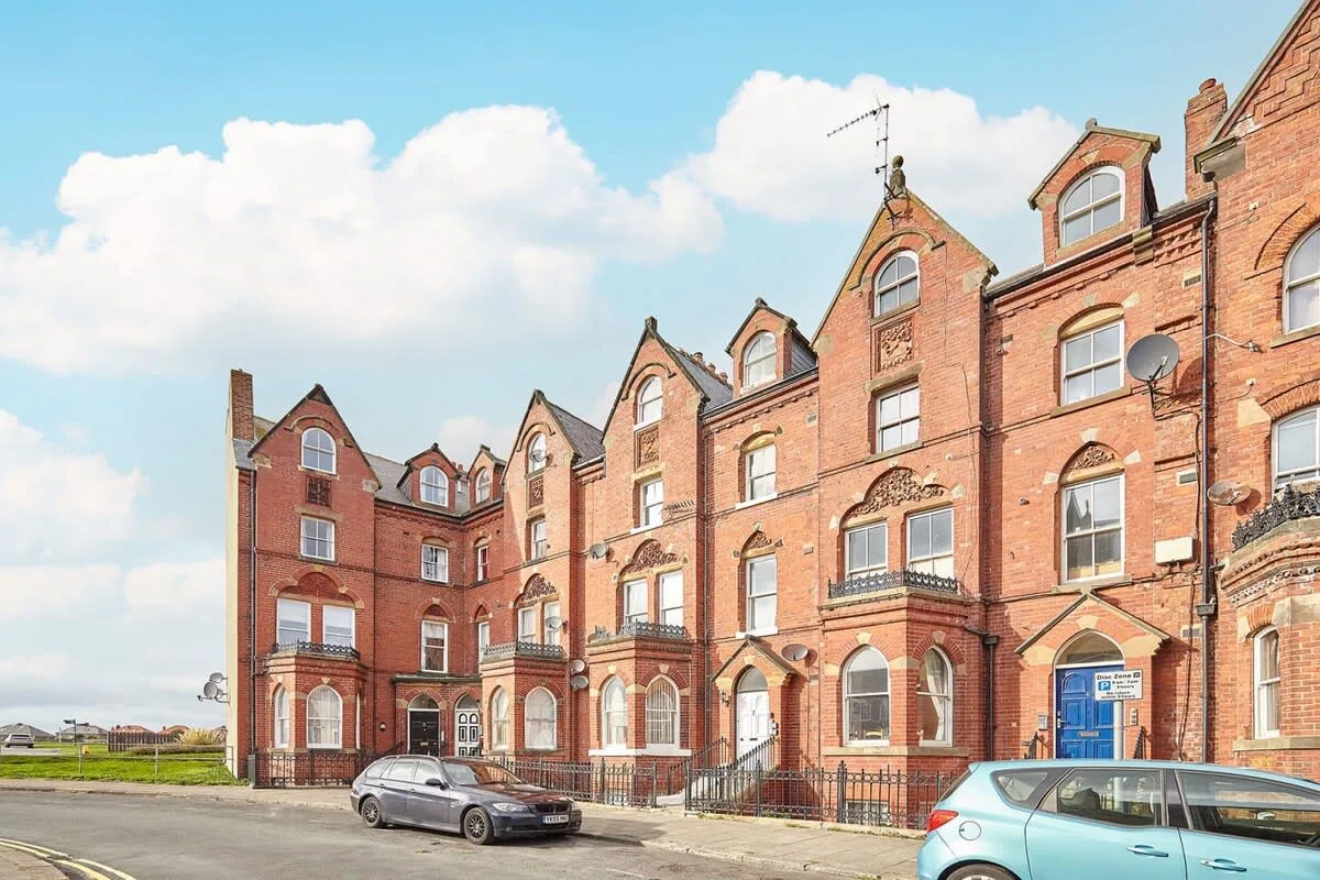 A row of red-brick buildings with ornate gables stands beside the street.