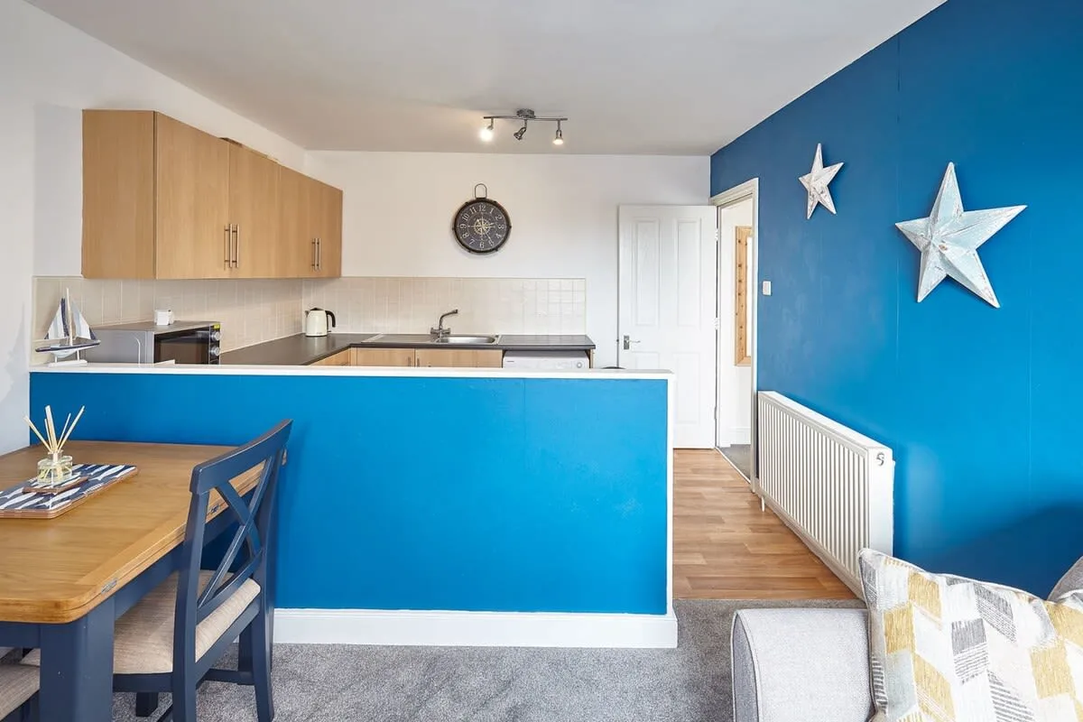 A kitchen and dining area with a blue counter and a wooden table.