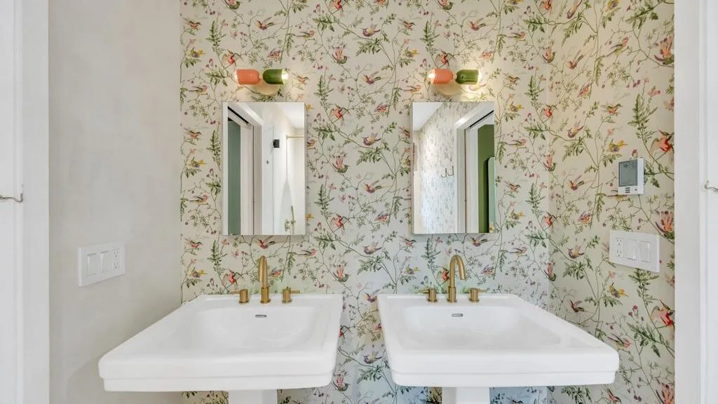 A bathroom vanity with two sinks, mirrors, and floral wallpaper.