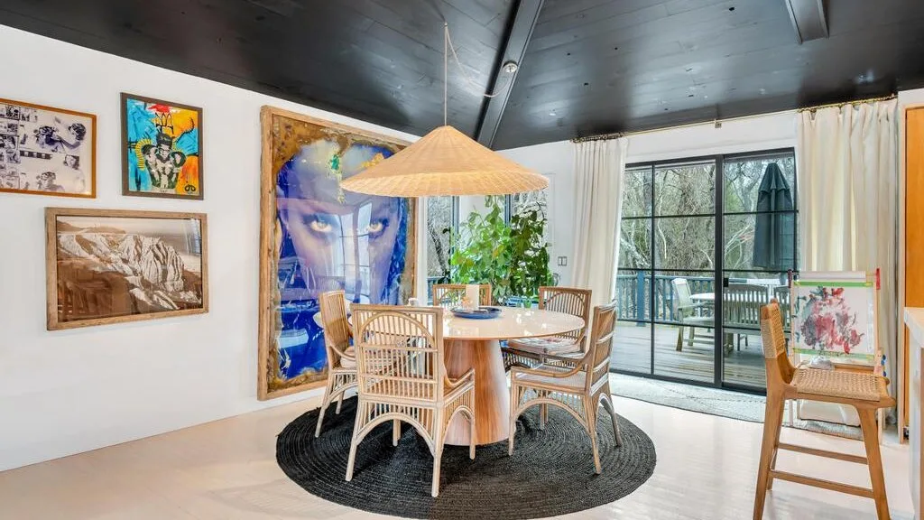 A dining area with a round table, woven seating, and large glass doors.