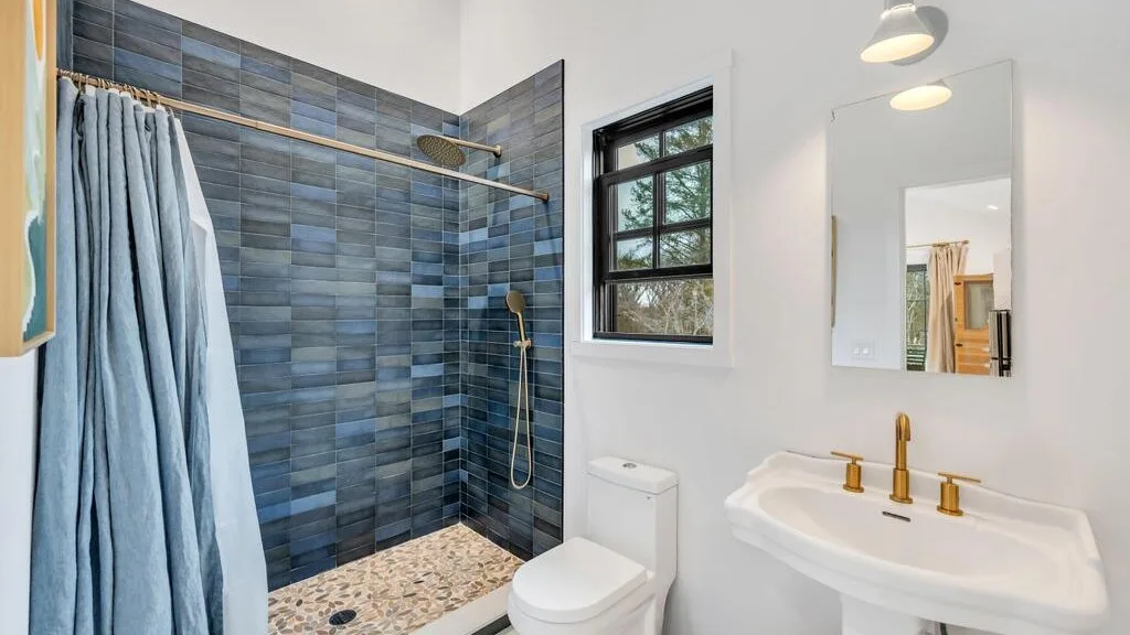 A bathroom with a tiled shower, toilet, and sink.