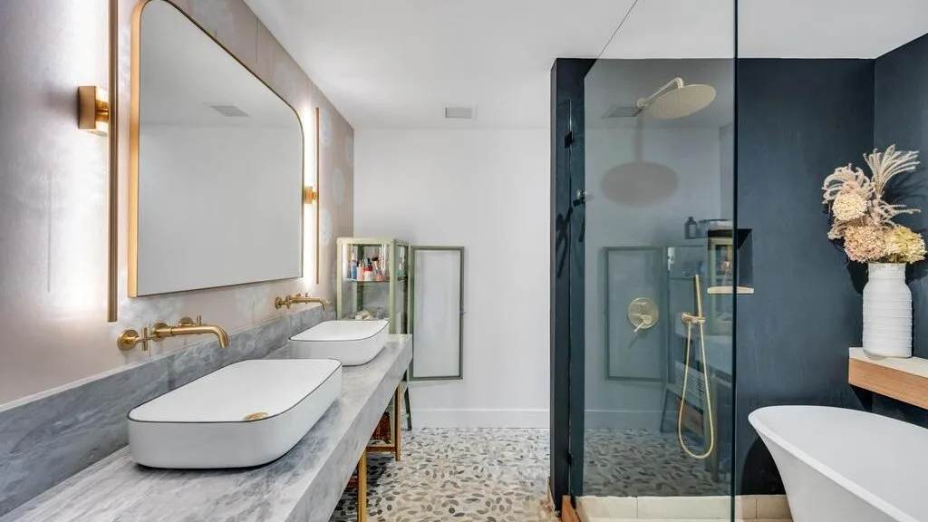 A modern bathroom with a double vanity, glass shower, and freestanding tub.