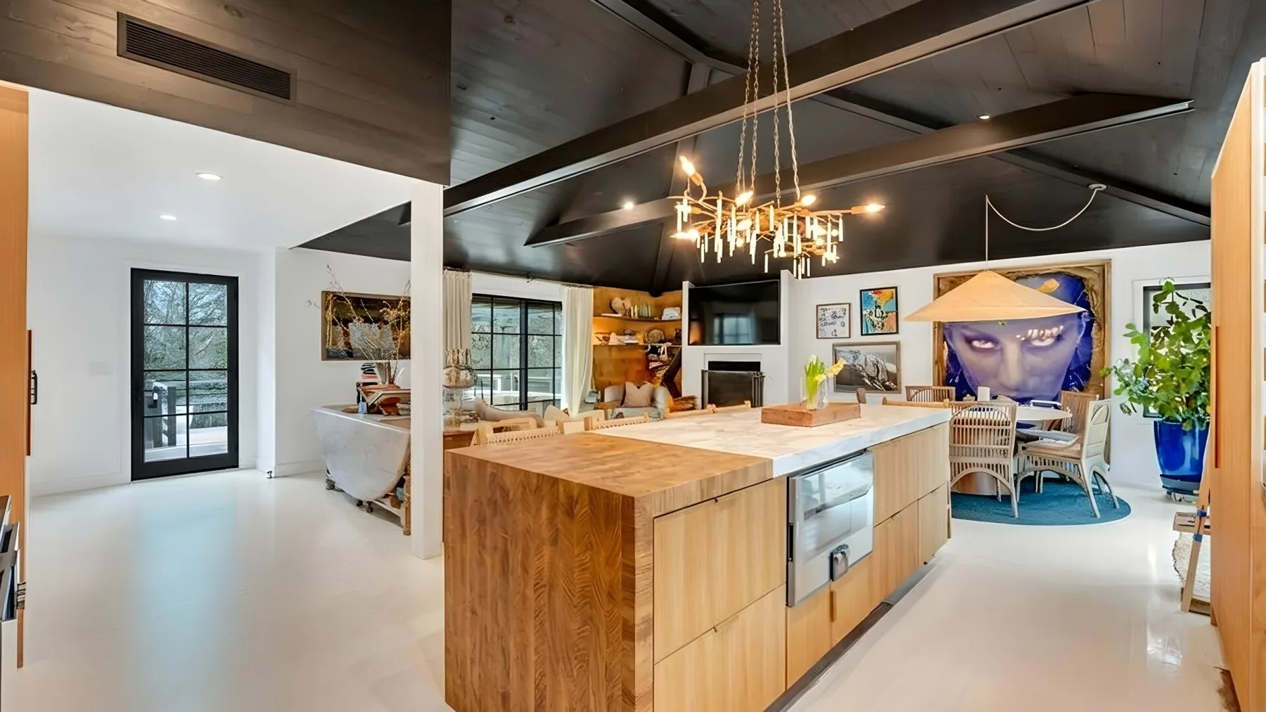 A modern kitchen with a large island, pendant lights, and an adjoining dining area.