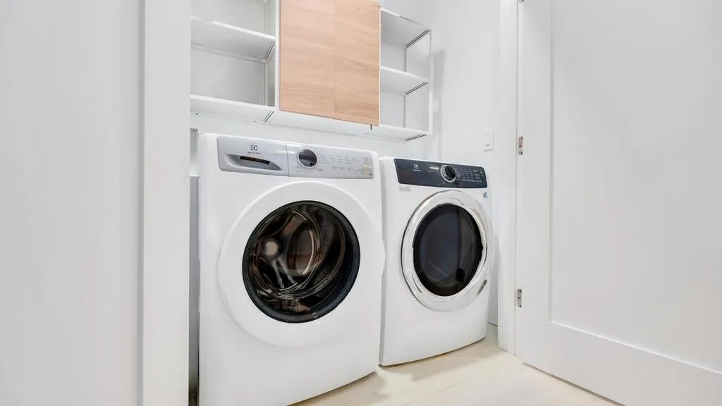 A laundry area with two front-loading machines beneath open shelving.