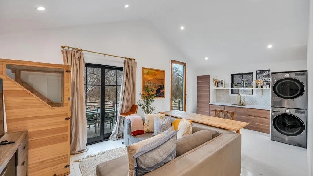 A bright living room with seating, a dining table, and a kitchen.