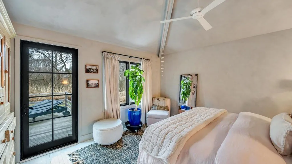 A bedroom with a bed, seating, and a glass door opening onto a balcony.