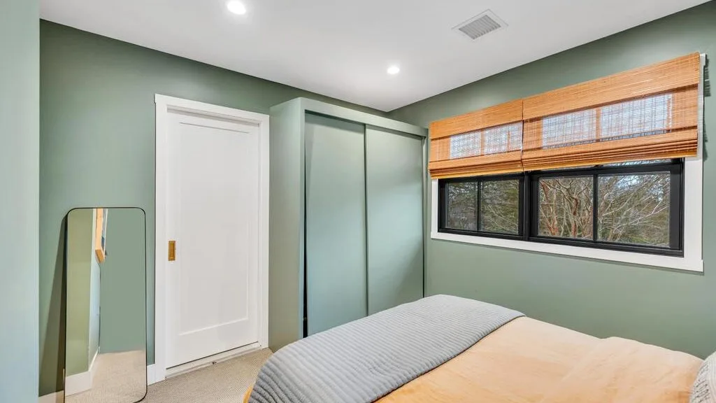 A bedroom with a bed, a wardrobe, and a window with wooden blinds.