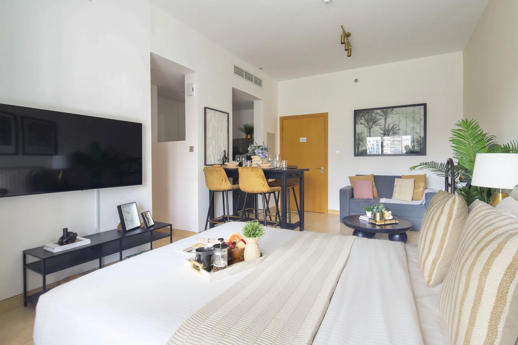 Una sala luminosa con una cama en primer plano y una zona de estar junto a la ventana.