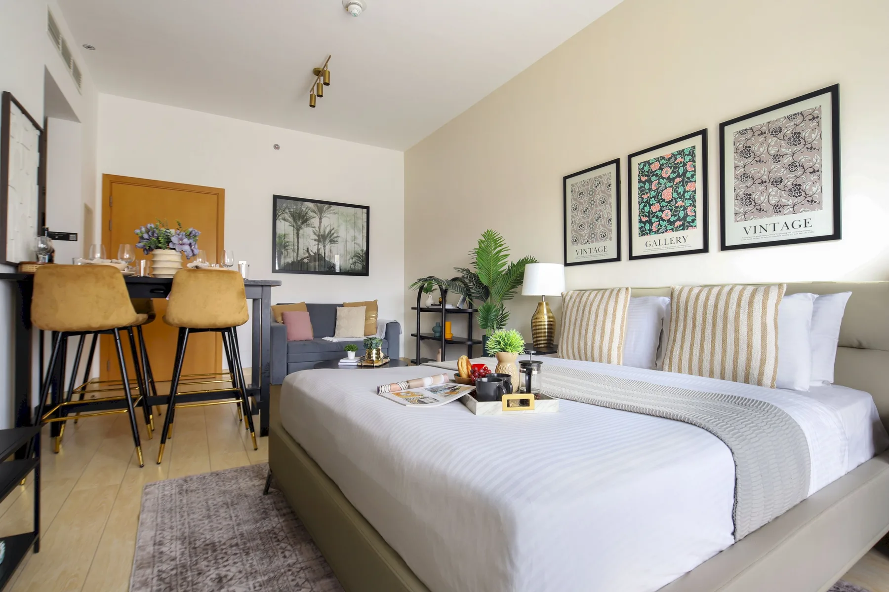 Un dormitorio luminoso con una cama bien tendida y un pequeño comedor.