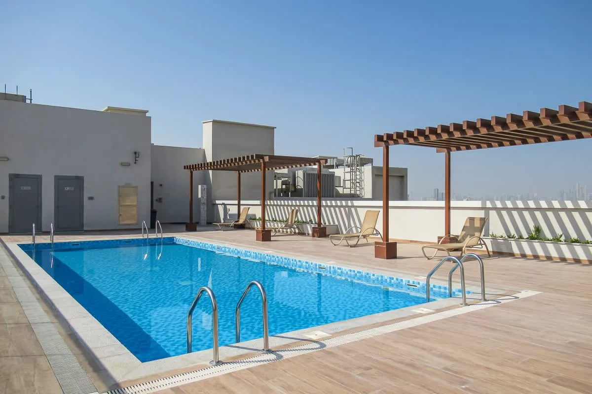 Una piscina en la azotea con pérgolas de madera y asientos para descansar.