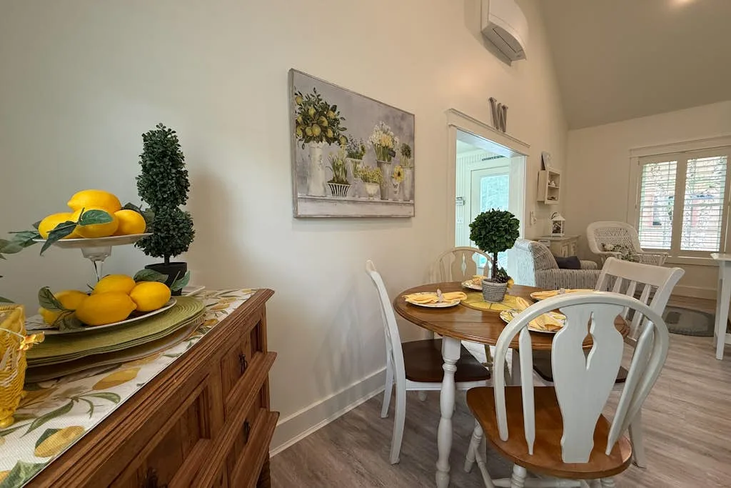 Dining area with a wooden table set with dishes and surrounded by chairs.