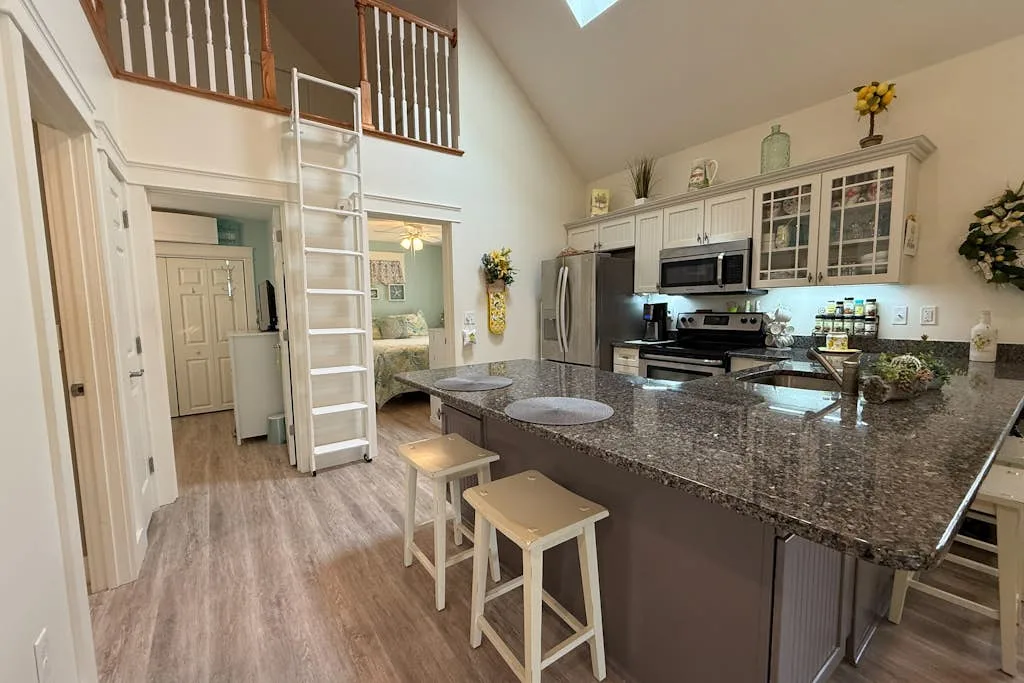 A kitchen with a large island, cabinets, and a ladder leading to an upper level.